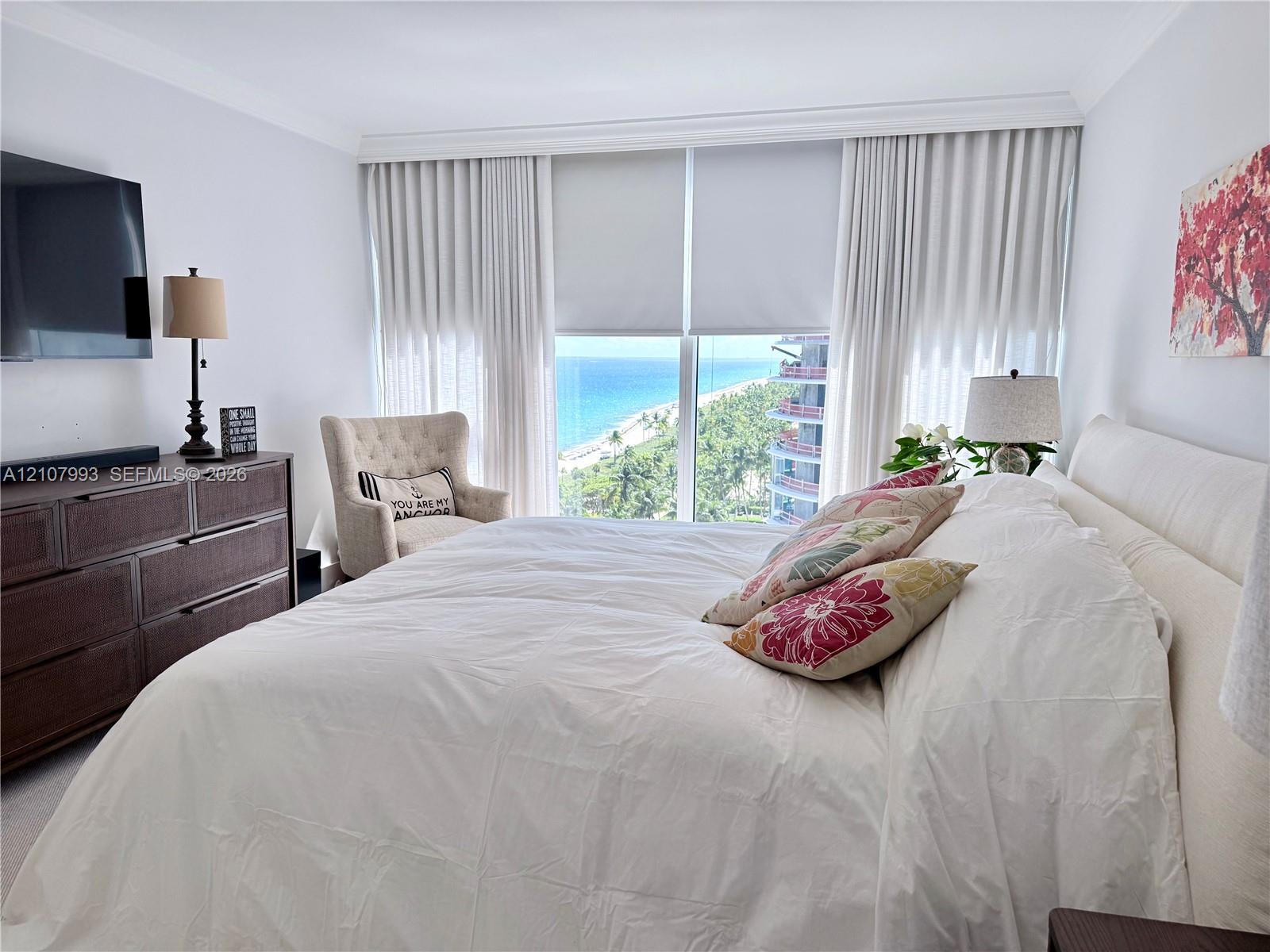 Floor-to-ceiling windows featuring coastal scenery, crown molding, and neutral wall-to-wall carpeting