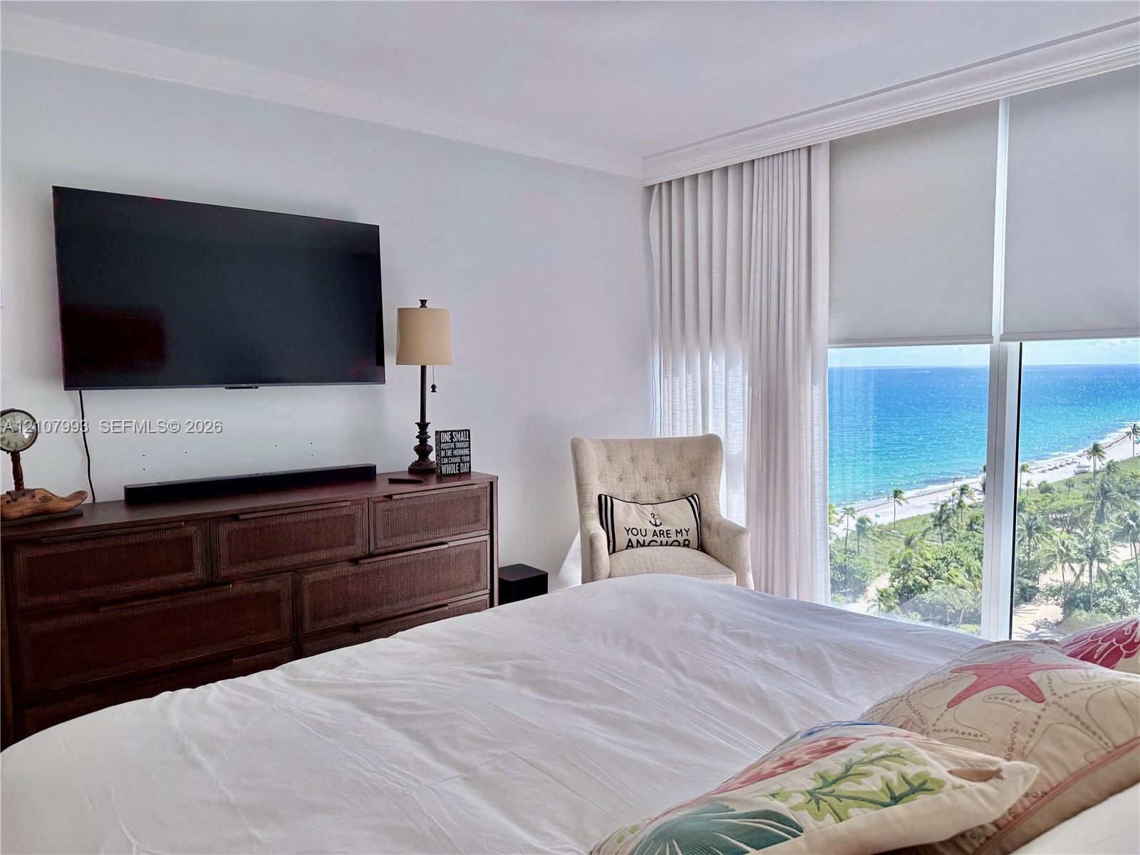 Floor-to-ceiling windows featuring ocean scenery, crown molding, and retractable privacy shades