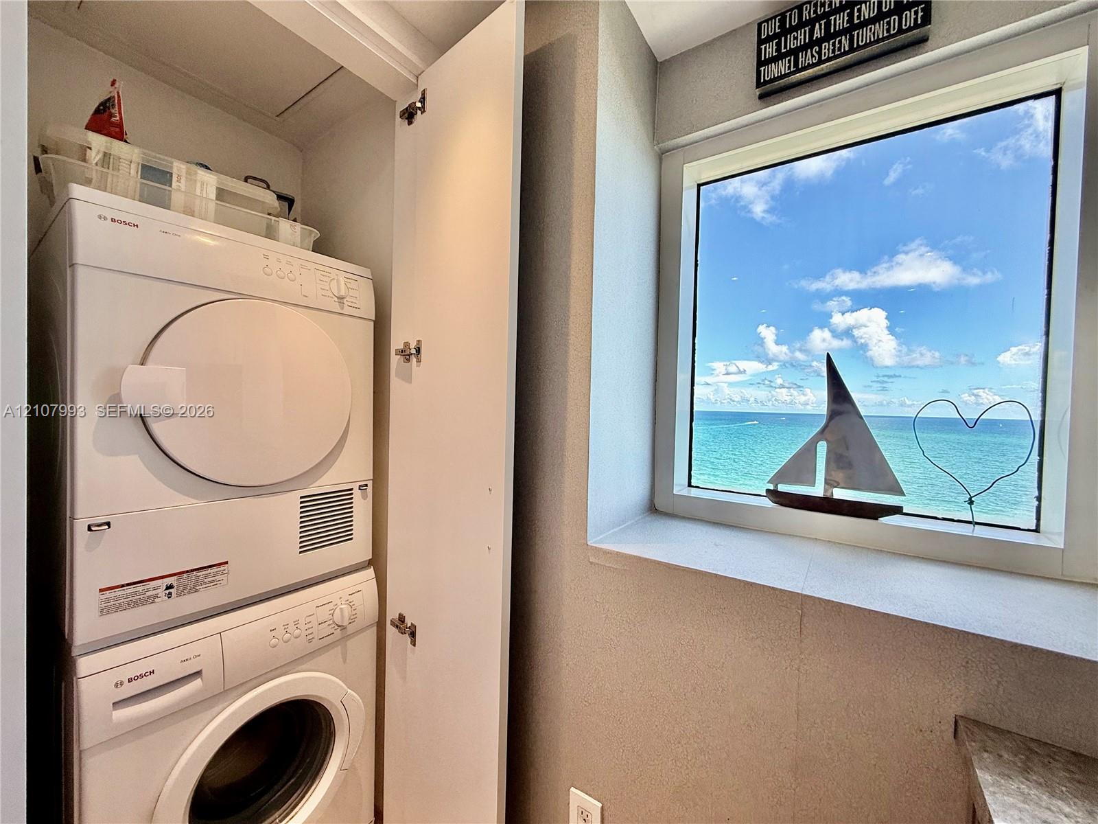 Stacked Bosch laundry center with a single-pane window featuring expansive ocean scenery
