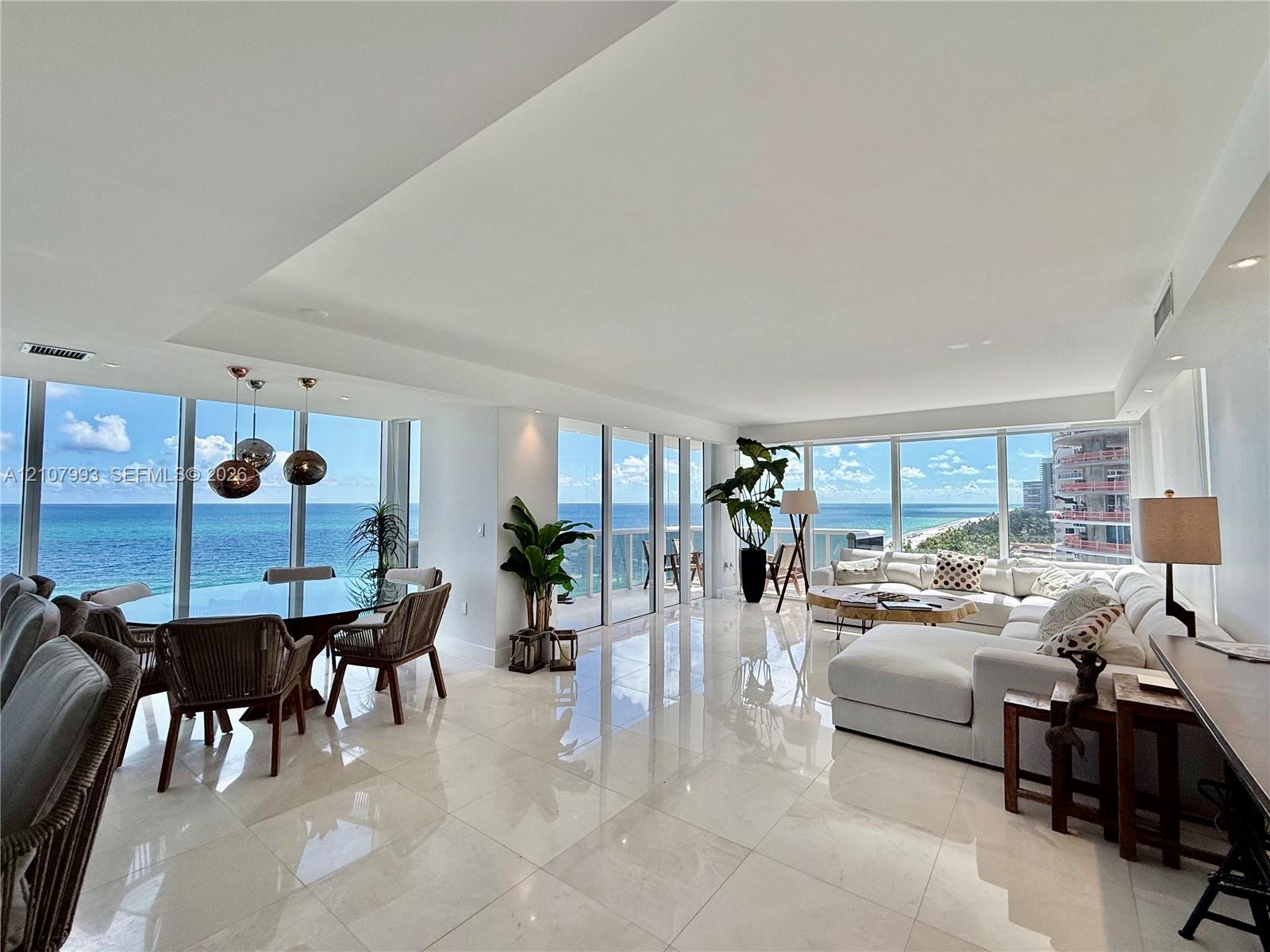 Open-concept interior featuring large-format stone flooring, floor-to-ceiling glass walls, recessed lighting, and modern pendant fixtures Open-concept interior featuring large-format stone flooring, floor-to-ceiling glass walls, recessed lighting, and modern pendant fixtures