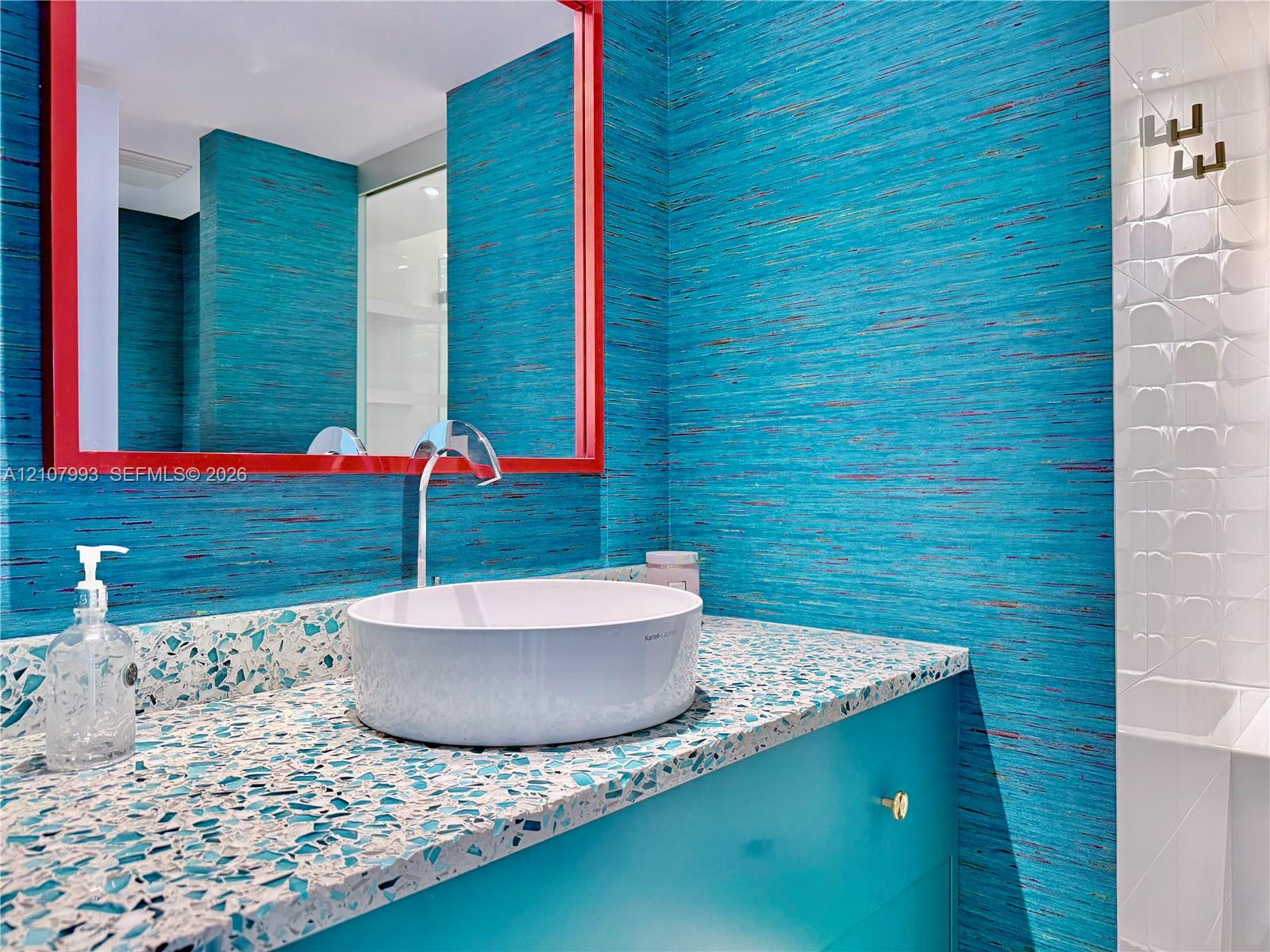 Custom vanity featuring a speckled composite countertop, a circular vessel sink, a high-arc chrome faucet, and textured wall coverings