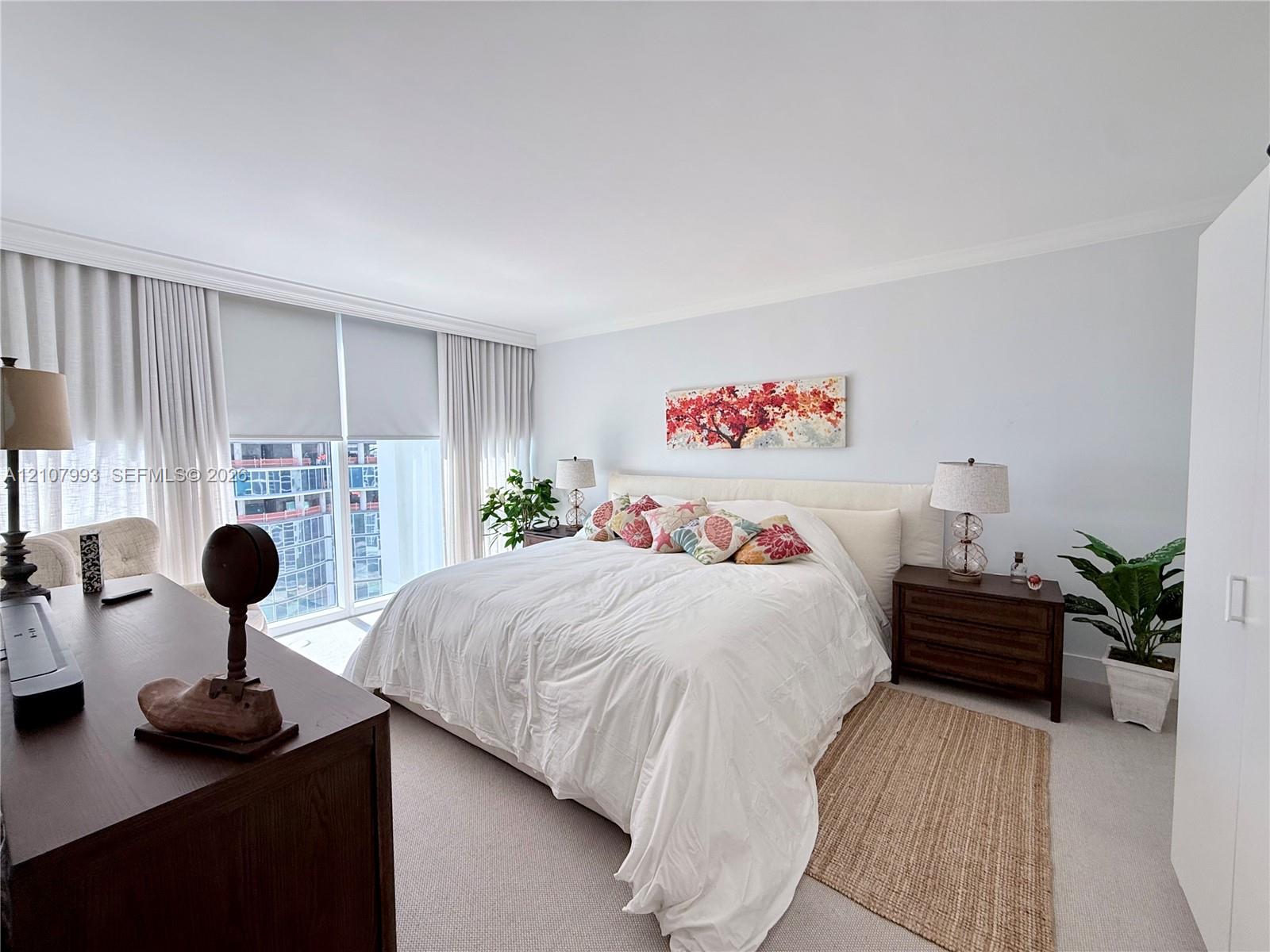 Floor-to-ceiling windows featuring automated roller shades, neutral carpeting, and crown molding