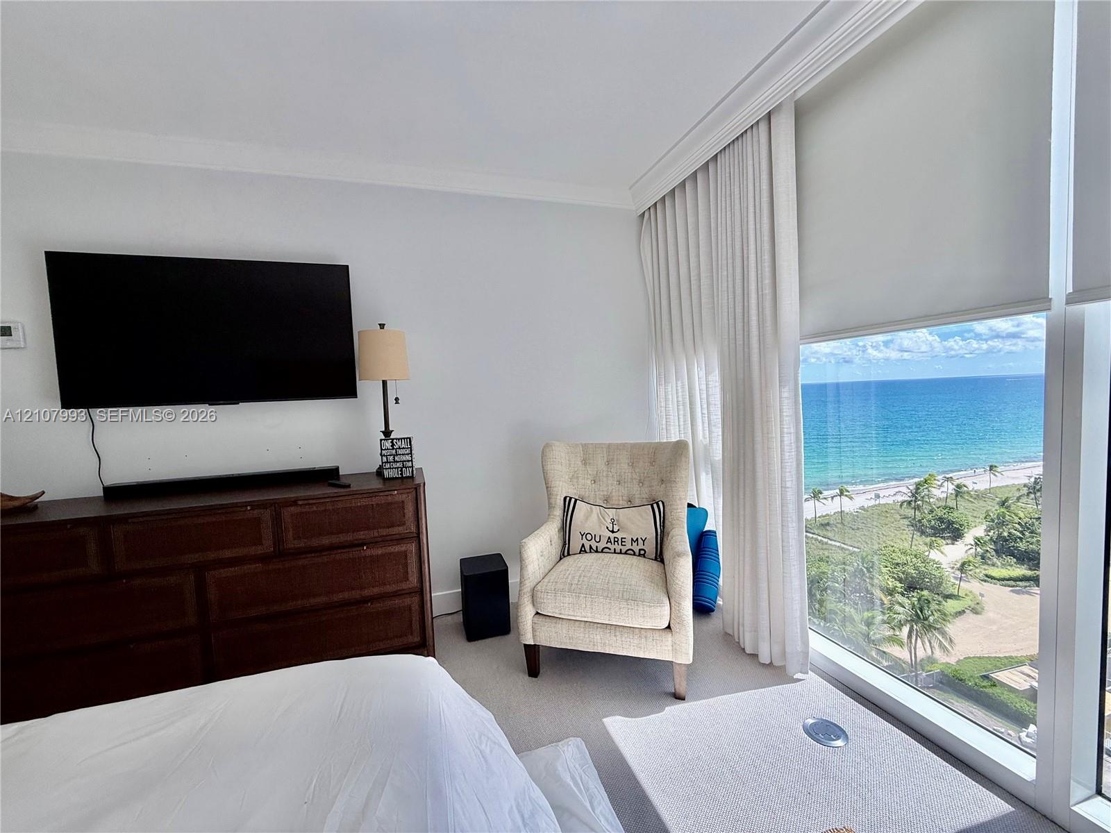 Floor-to-ceiling windows, neutral carpeting, crown molding, and direct oceanfront scenery