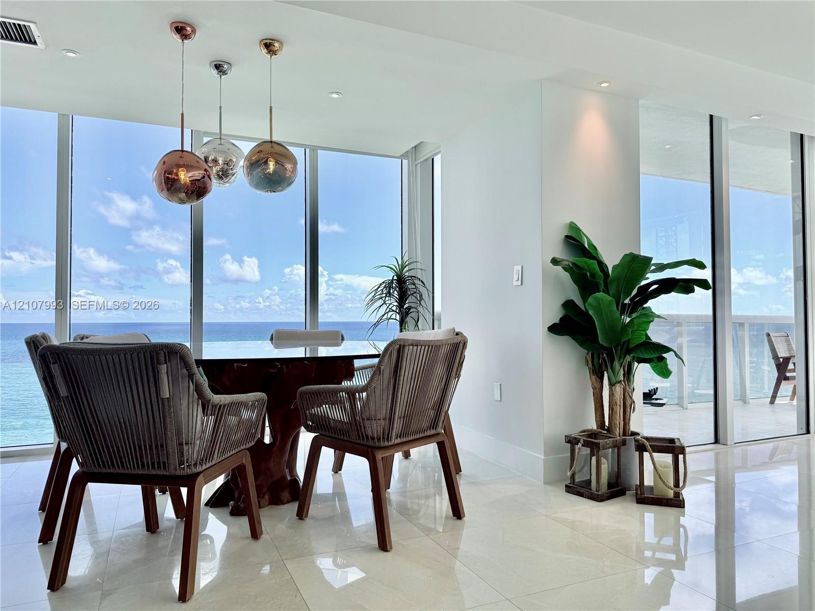 Floor-to-ceiling windows, polished tile flooring, and metallic spherical pendant lighting