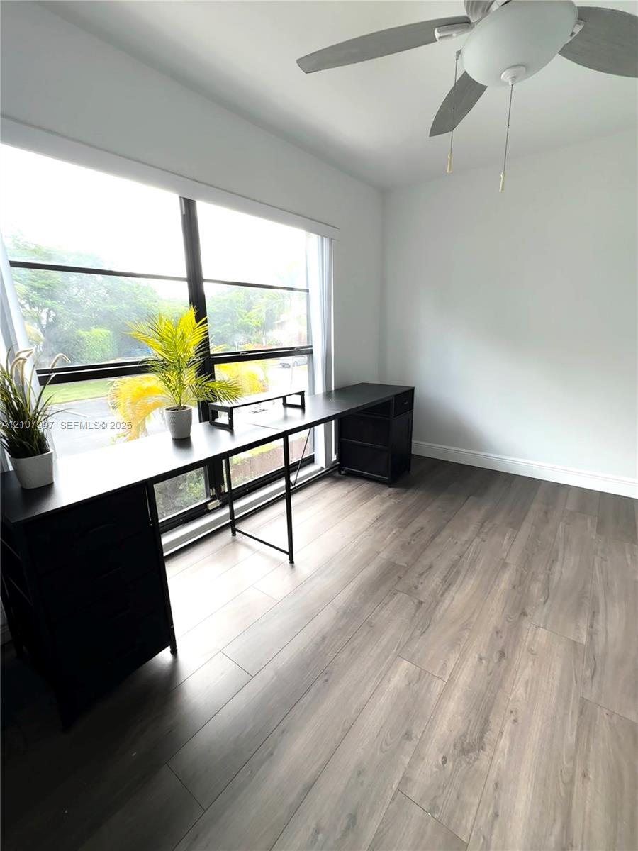 Third bedroom Large floor-to-ceiling windows with dark framing, wood-finish flooring, and a ceiling fan with integrated lighting