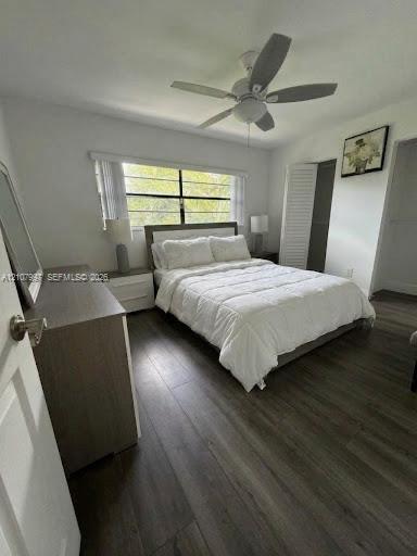 Second bedroom featuring wood-finish flooring, and floor-to-ceiling louvered closet doors. Bed linens virtually stages