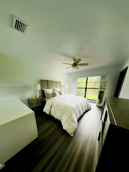 Master bedroom featuring wood-finish flooring, a ceiling fan with integrated lighting, floor to ceiling windows. Bed linen is virtually staged.