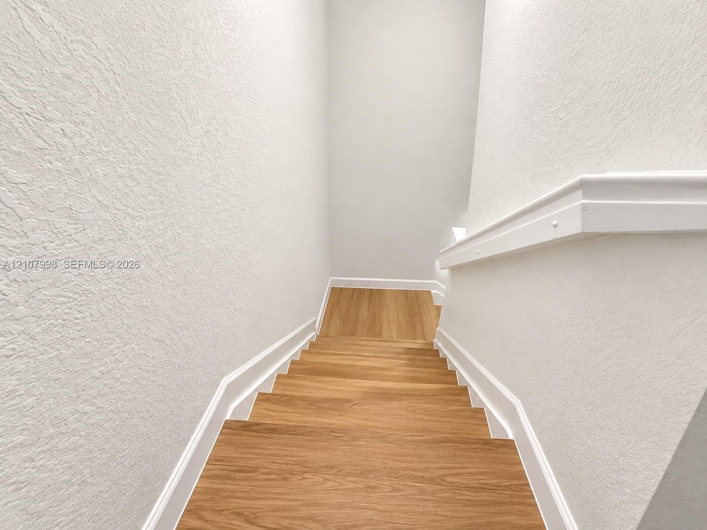Staircase featuring wood-finish treads and a white painted handrail