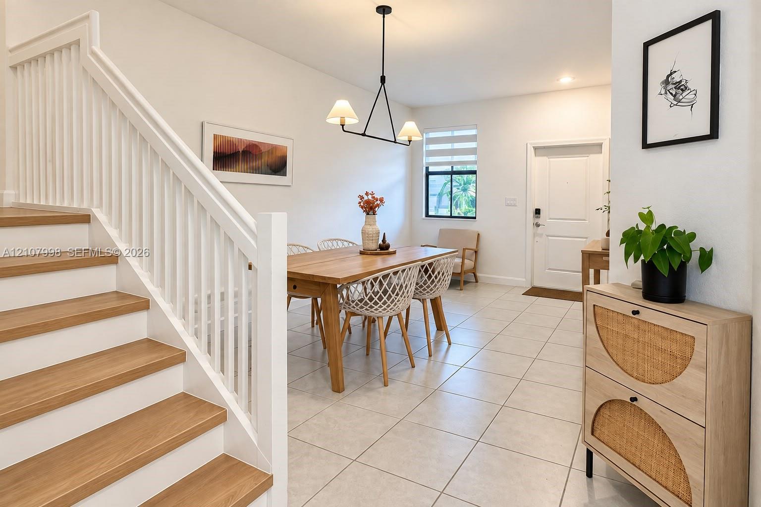 Staircase with wood-finish treads and white balusters, ceramic tile flooring, modern geometric pendant lighting, and neutral wall tones