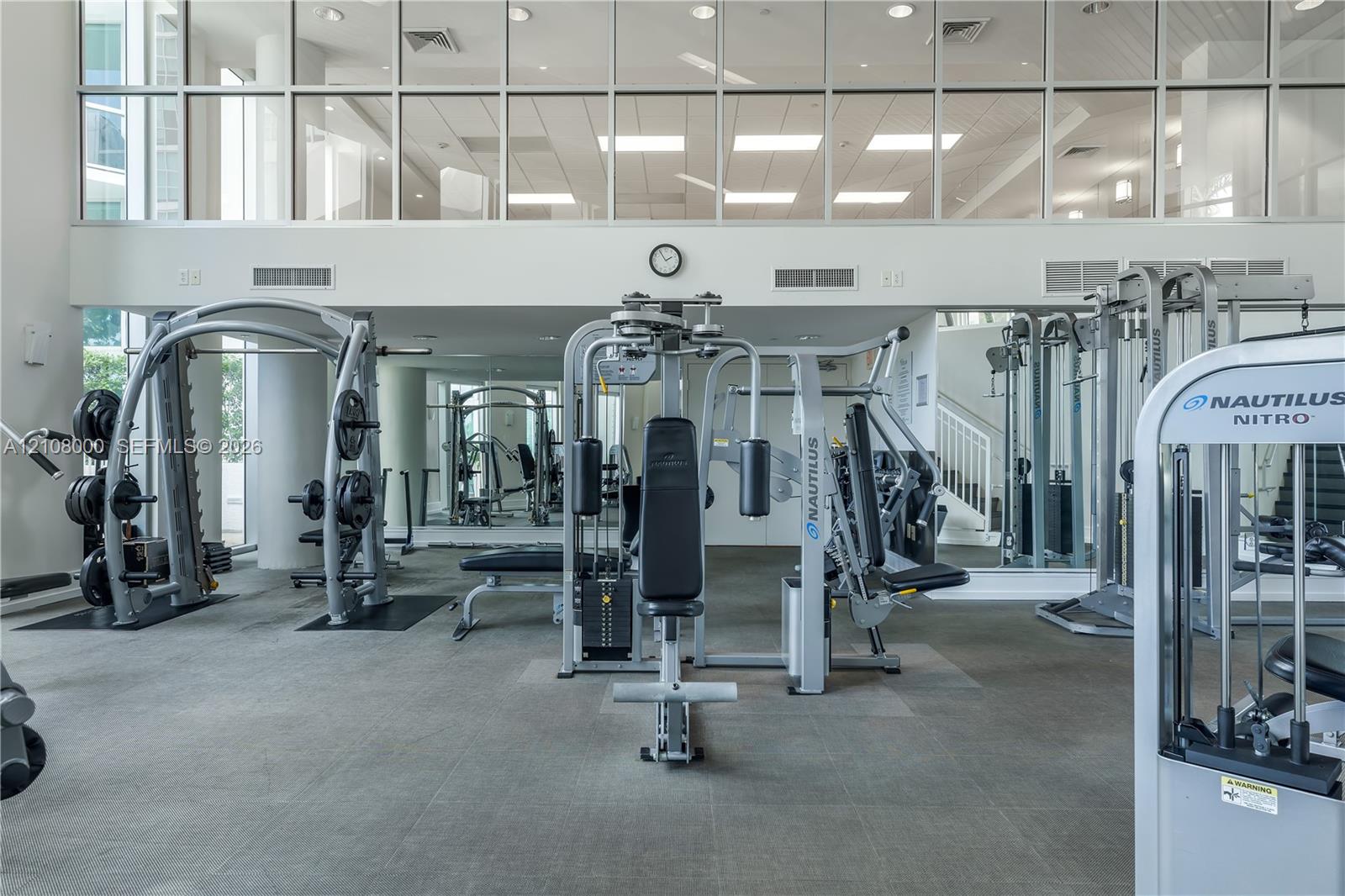 Fitness center featuring floor-to-ceiling windows, full-wall mirrors, and high ceilings