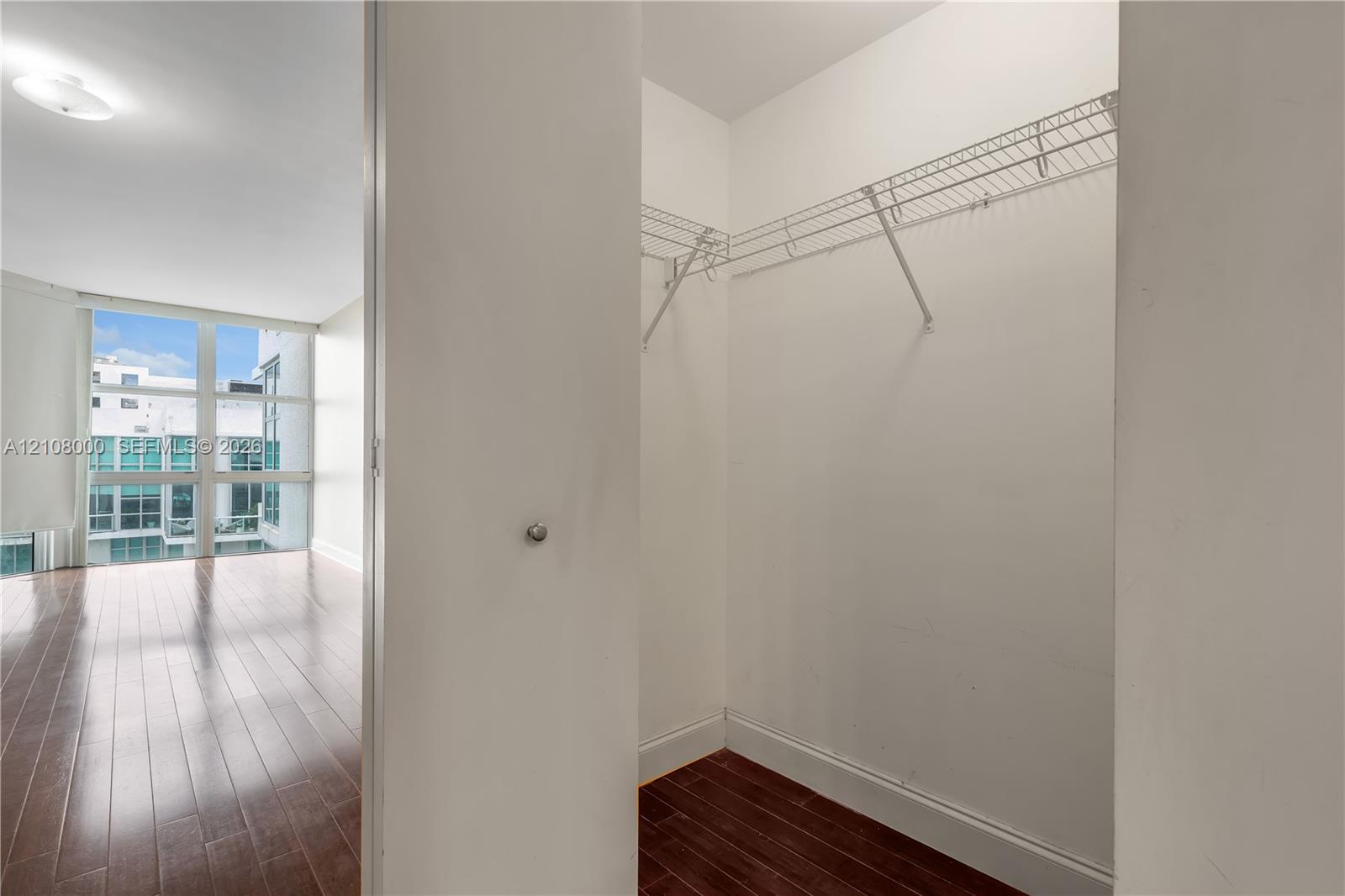 Walk-in closet featuring wire shelving, white interior walls, and wood-finish flooring