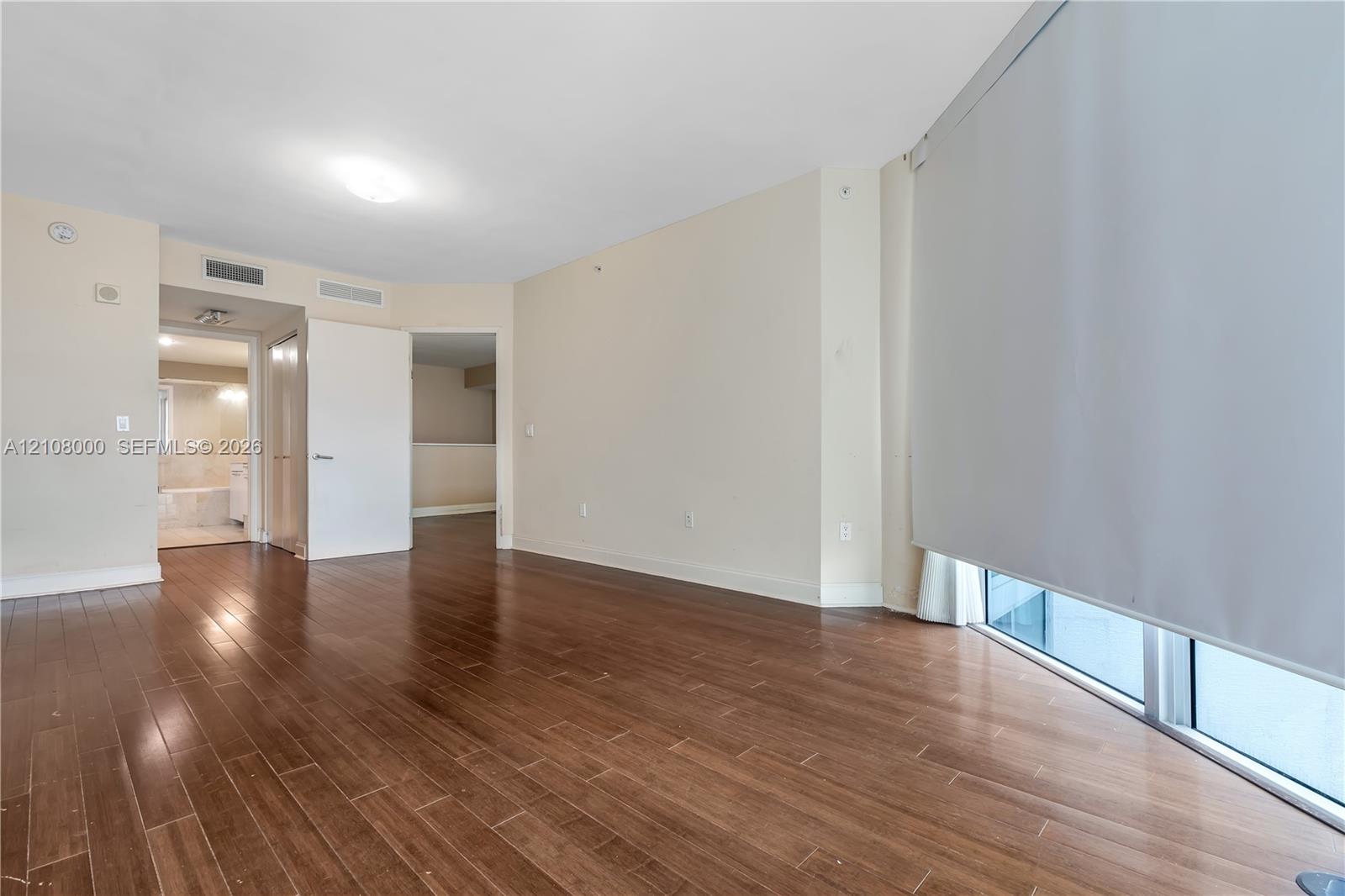 Wood-finish flooring, floor-to-ceiling windows with roller shades, and neutral wall tones