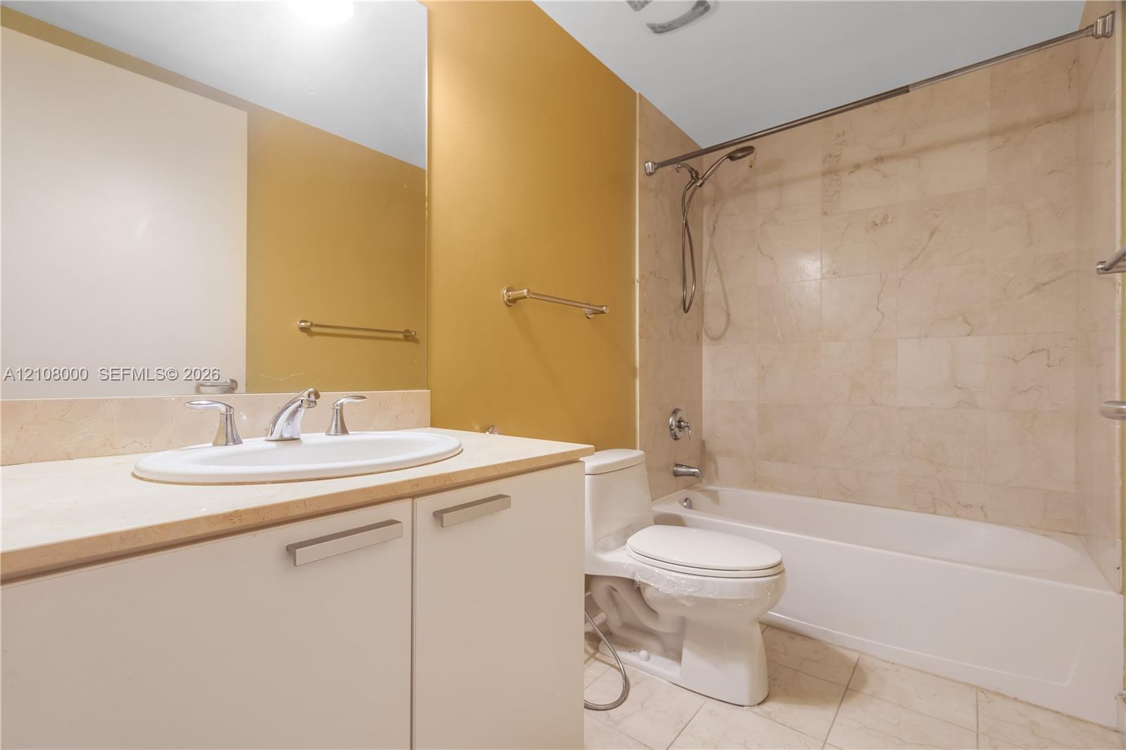 Bathroom featuring a vanity with a stone countertop, oval undermount sink, stone tile tub surround, and a wall-to-wall mirror