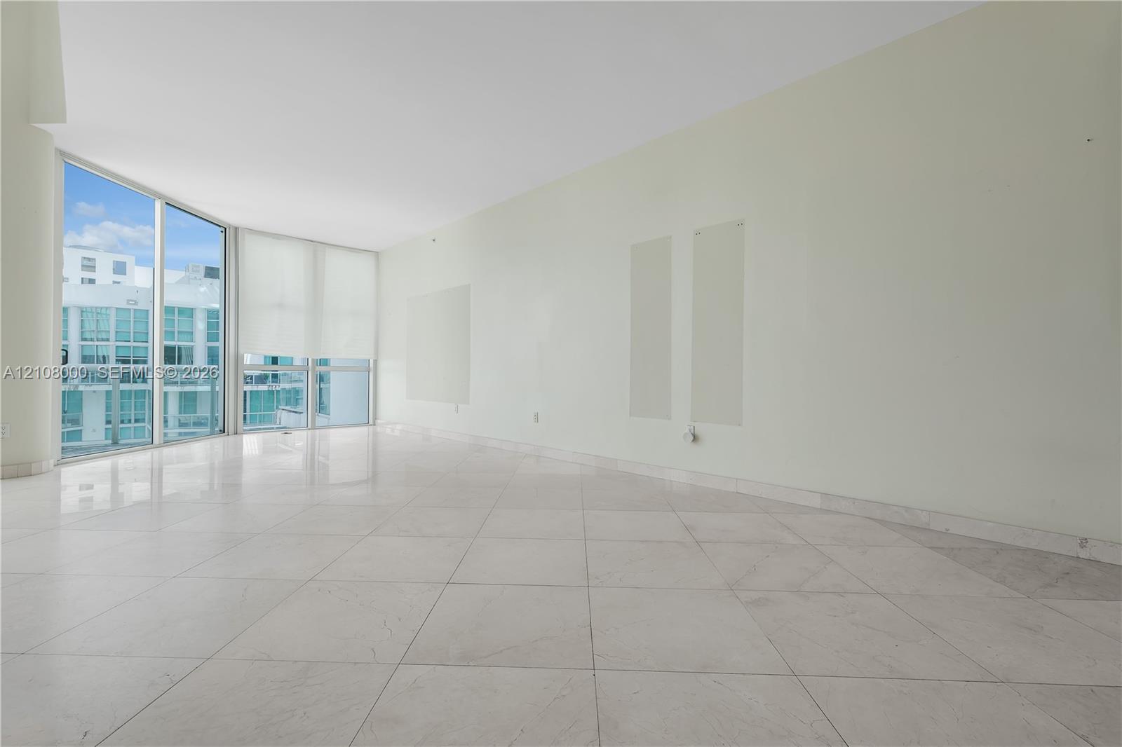 Open-concept room featuring floor-to-ceiling glass panels, large-format tile flooring, and a structural concrete column