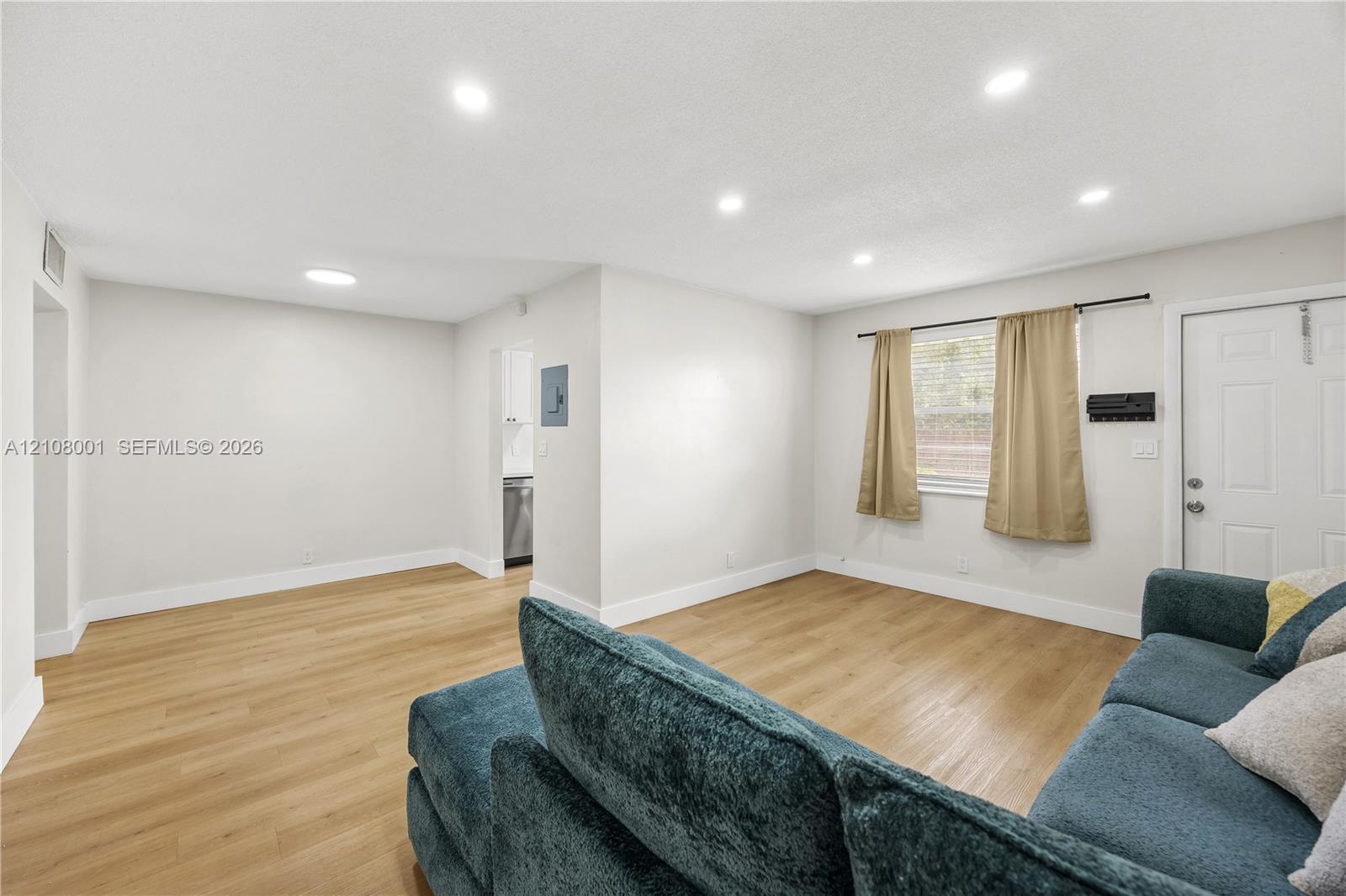 Open interior featuring wood-finish flooring, recessed lighting, and a paneled exterior entry door