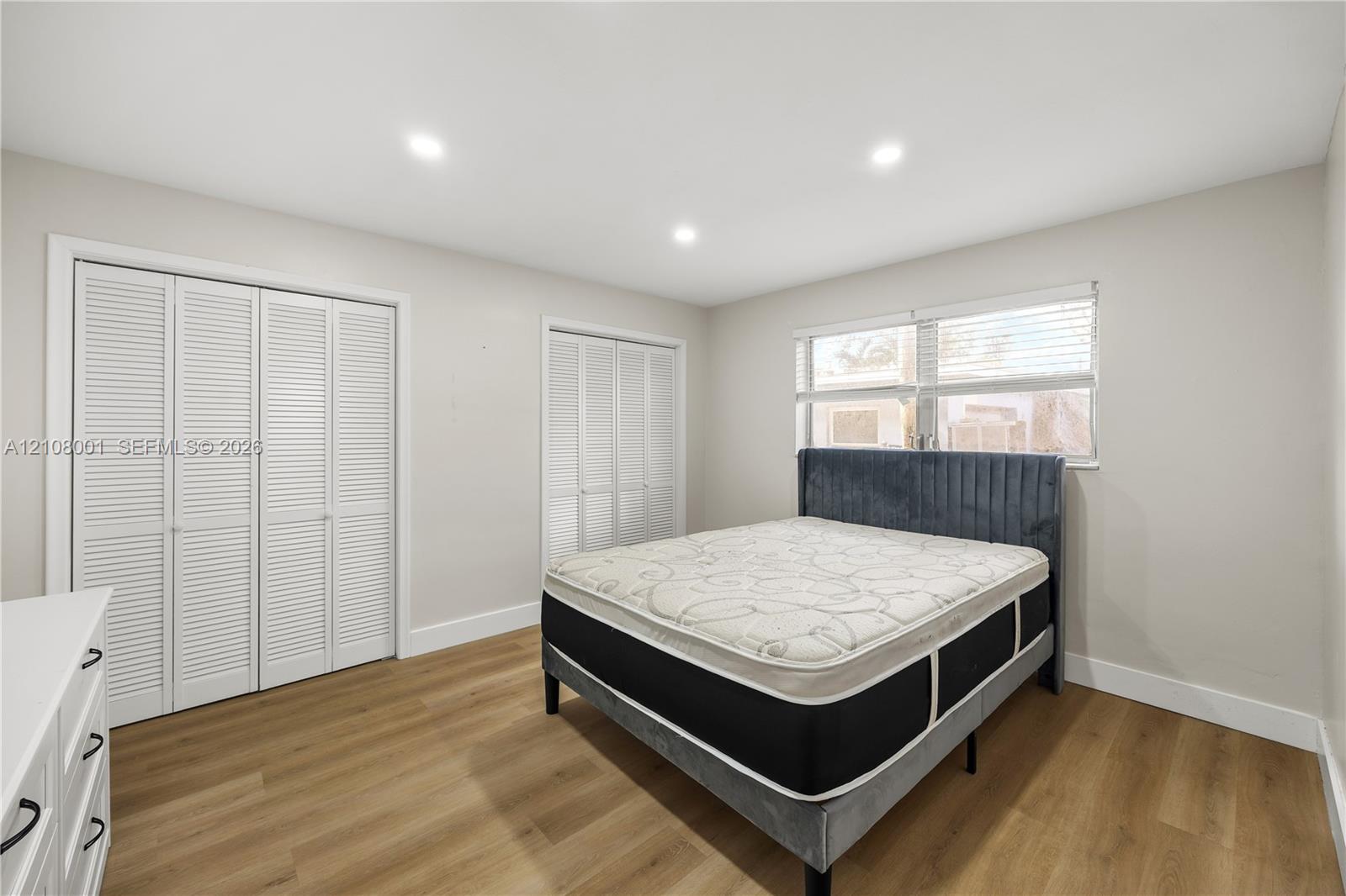 Neutral-toned interior featuring wood-finish flooring, recessed lighting, and two sets of louvered-style closet doors