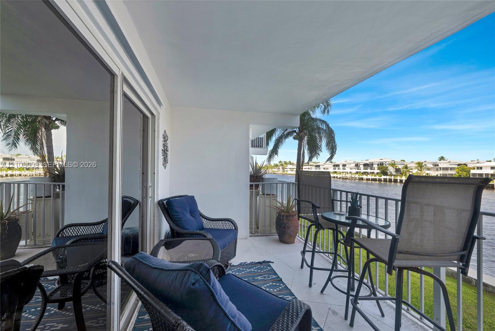 Covered balcony featuring tiled flooring, metal railing, and direct water exposure
