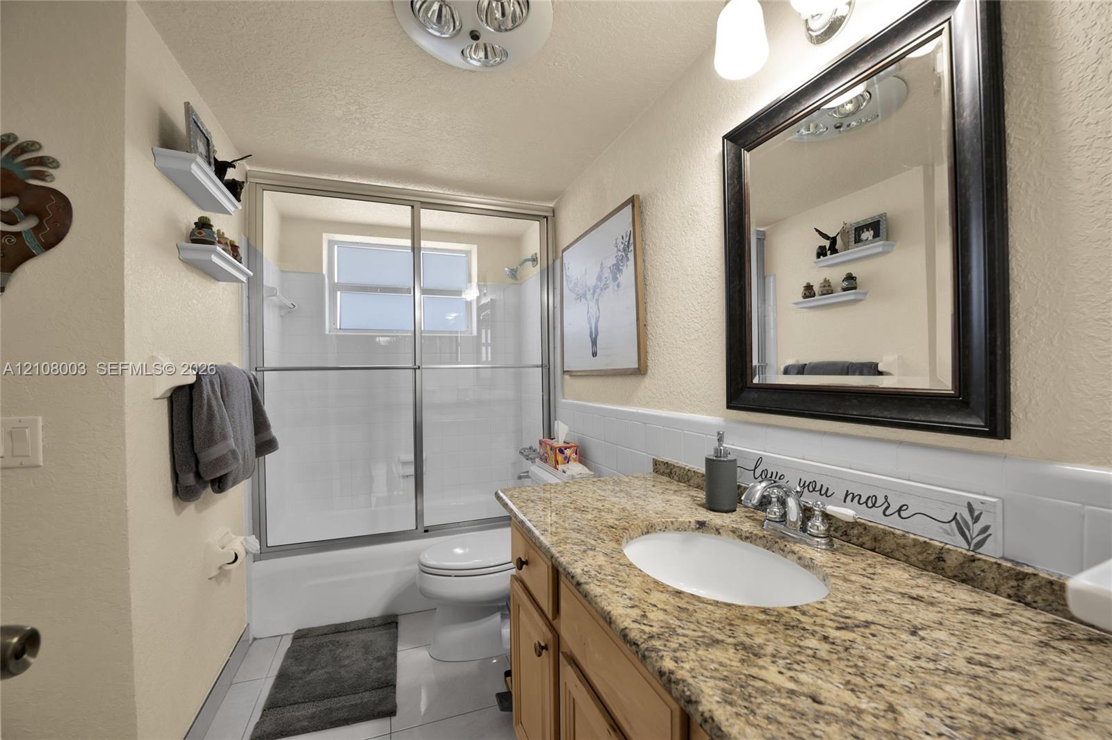 Bathroom featuring a vanity with a stone-finish countertop, undermount oval sink, chrome dual-handle faucet, and built-in wood-finish cabinetry