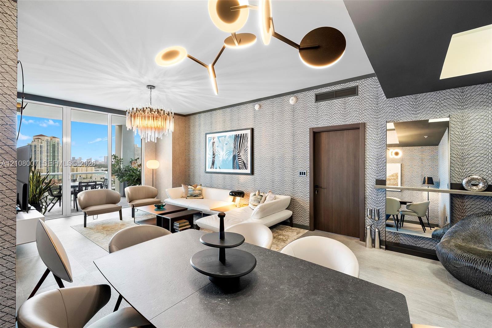Floor-to-ceiling windows, modern multi-tiered chandelier, patterned wall treatment, wood-finish interior door, and tile flooring