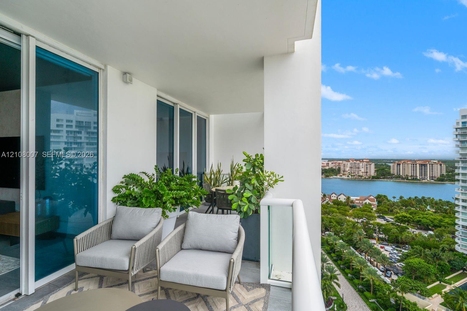 Covered balcony featuring floor-to-ceiling glass doors, a glass panel railing, and stone tile flooring