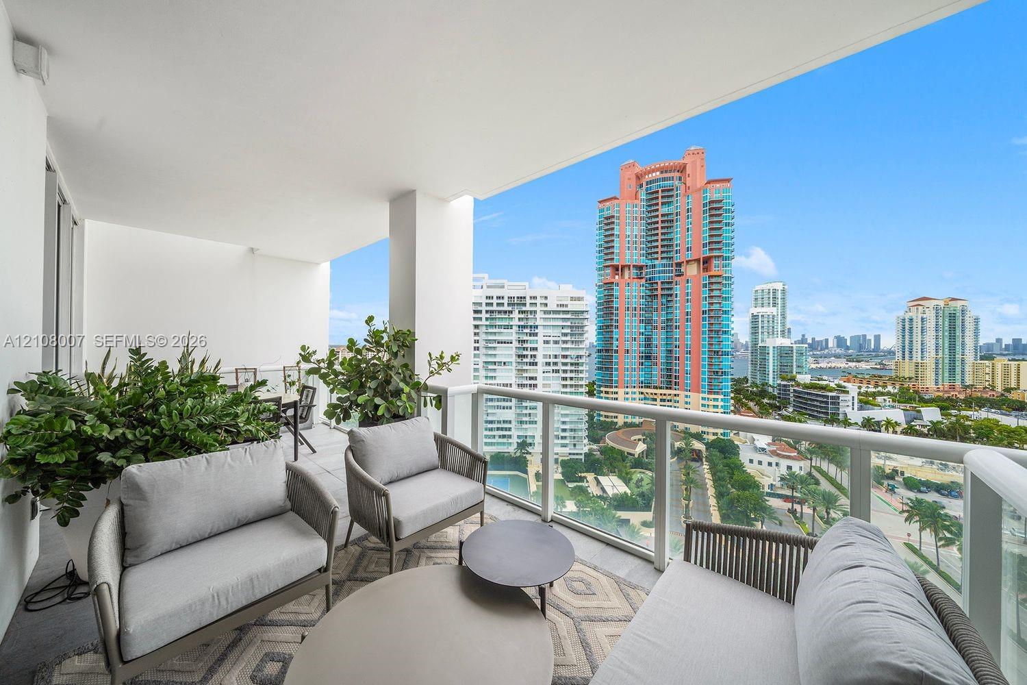 Covered balcony featuring neutral stone flooring, a glass panel railing, and expansive city skyline scenery