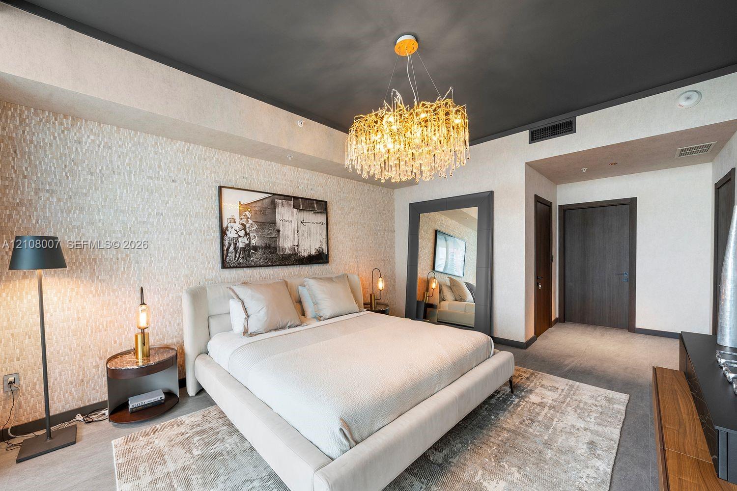 Textured stone feature wall with a contrasting dark ceiling, statement multi-tiered crystal chandelier, and dark-finish paneled interior doors