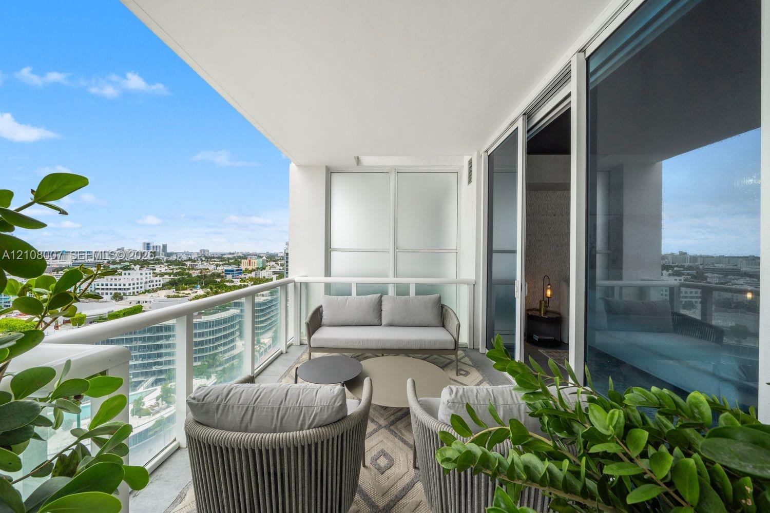Covered private balcony featuring glass panel railings, concrete flooring, and expansive sliding glass doors