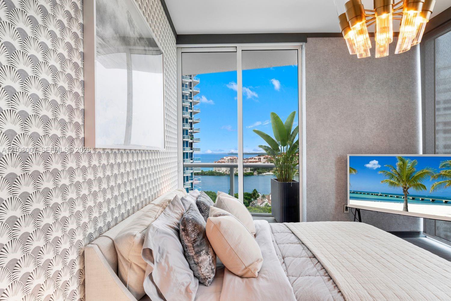 Floor-to-ceiling glass sliding doors opening to a private balcony, patterned wall treatment, textured accent wall, and multi-tier brass chandelier