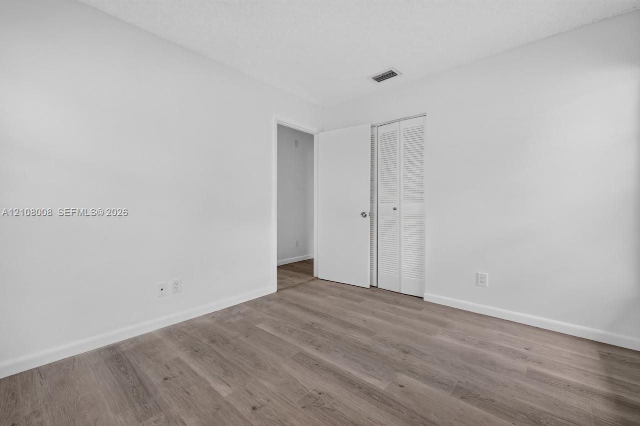 Room featuring neutral wall paint, wood-finish flooring, and a closet with bifold louvered doors