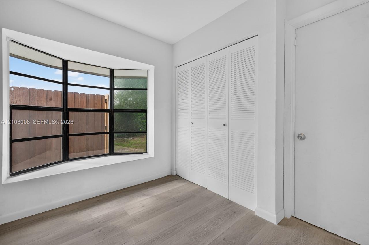 Multi-panel bay window with black framing, wood-finish flooring, and built-in closet with louvered doors