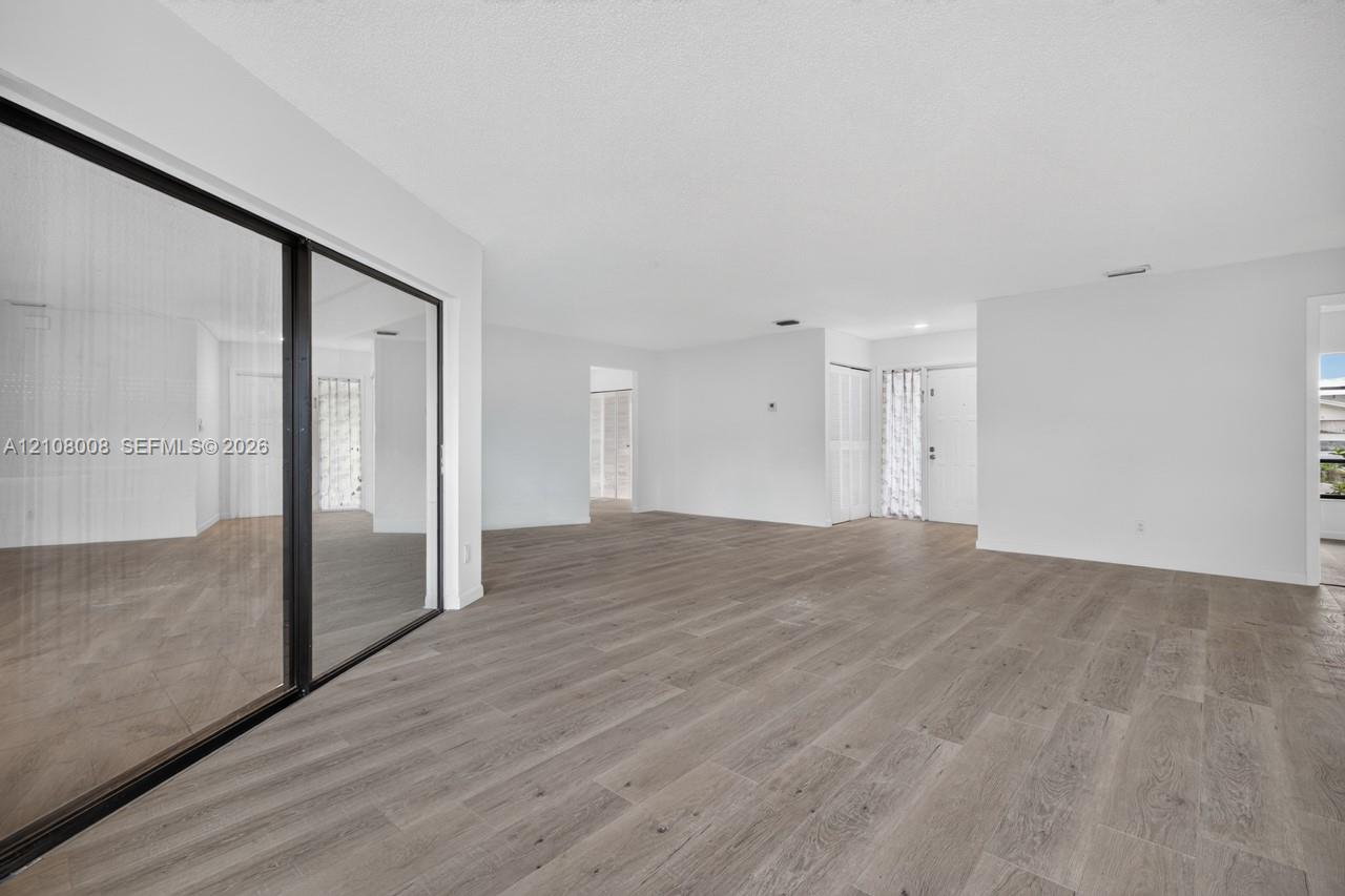 Interior space featuring wood-finish flooring, floor-to-ceiling sliding glass doors with black frames, and recessed lighting