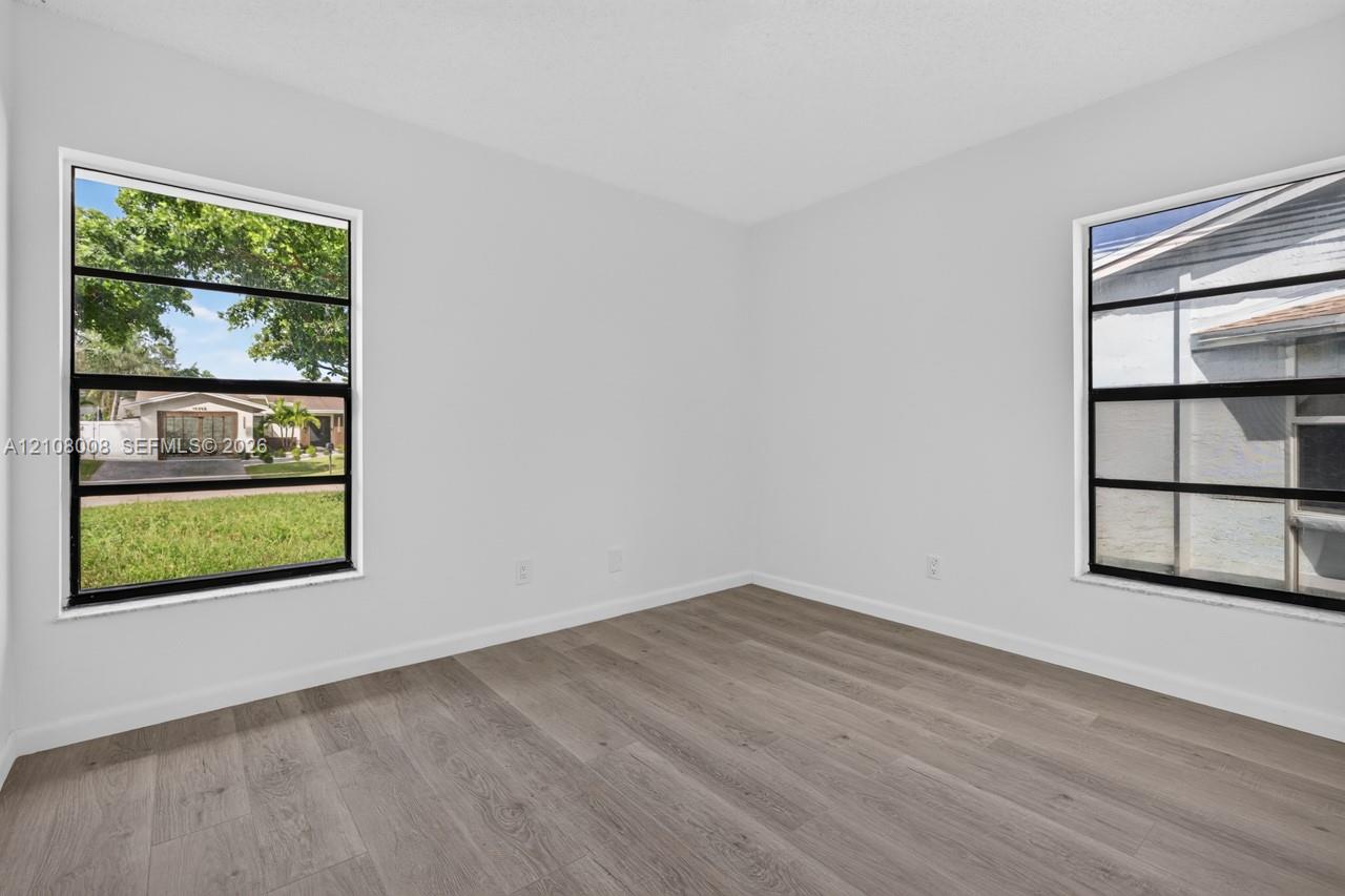 Neutral-toned interior room featuring wood-finish flooring and dual horizontal sliding windows with black frames