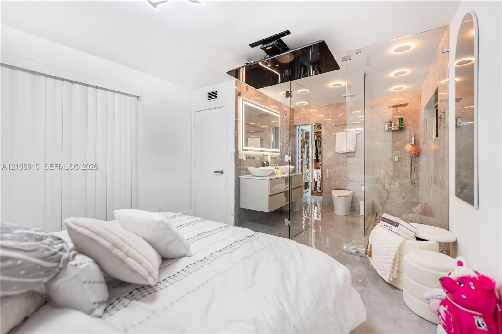 En-suite bathroom featuring a glass-enclosed shower, dual-sink floating vanity, backlit mirror, and recessed ceiling lighting