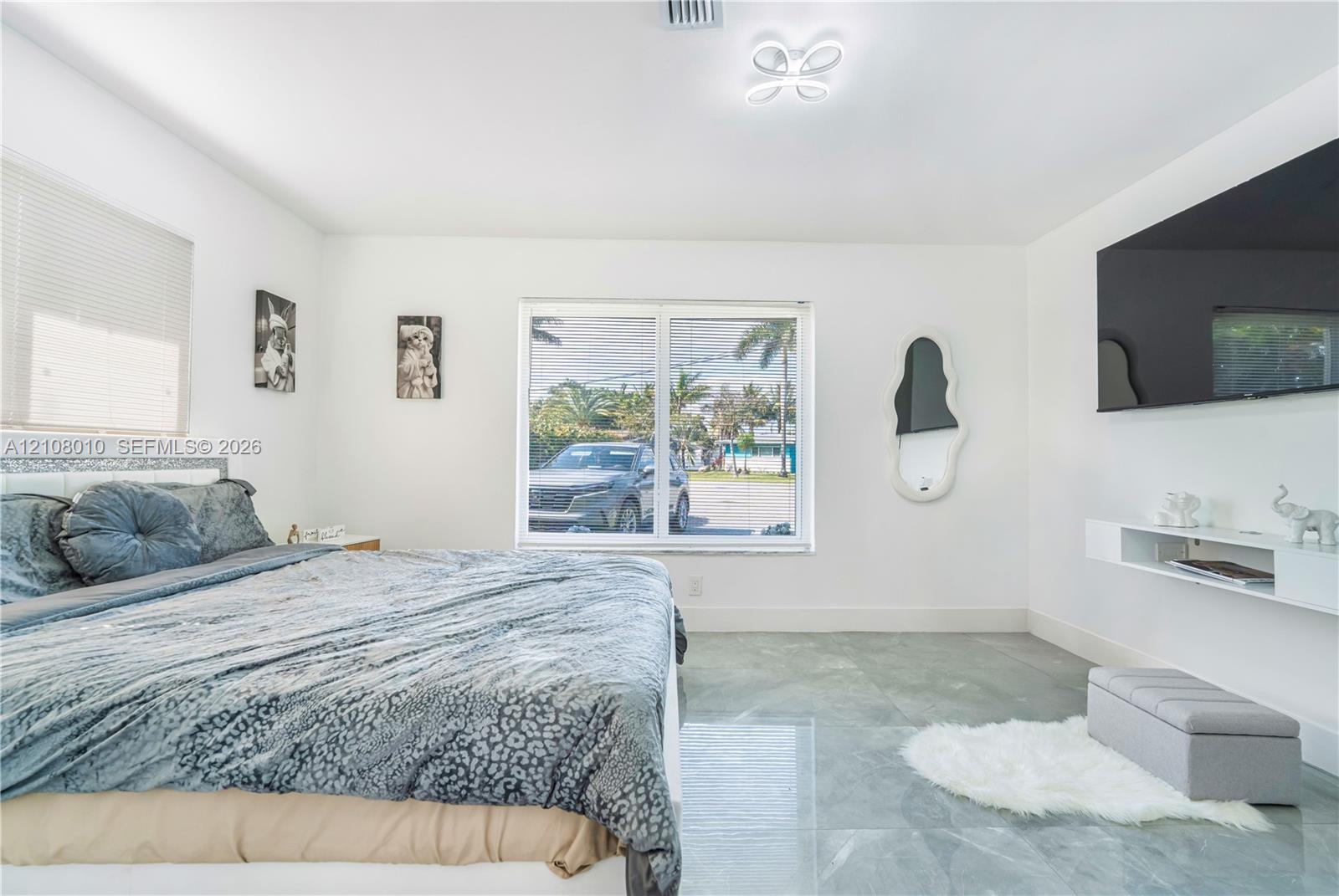 Spacious room featuring polished stone-finish flooring, a contemporary multi-arm flush mount ceiling light, and a white wall-mounted floating media console