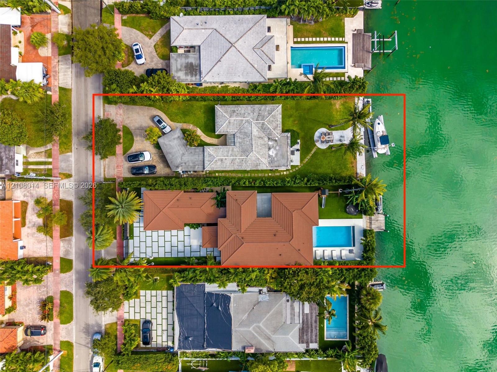 Waterfront property featuring a private boat dock, swimming pool, large paved patio, and multi-car driveway