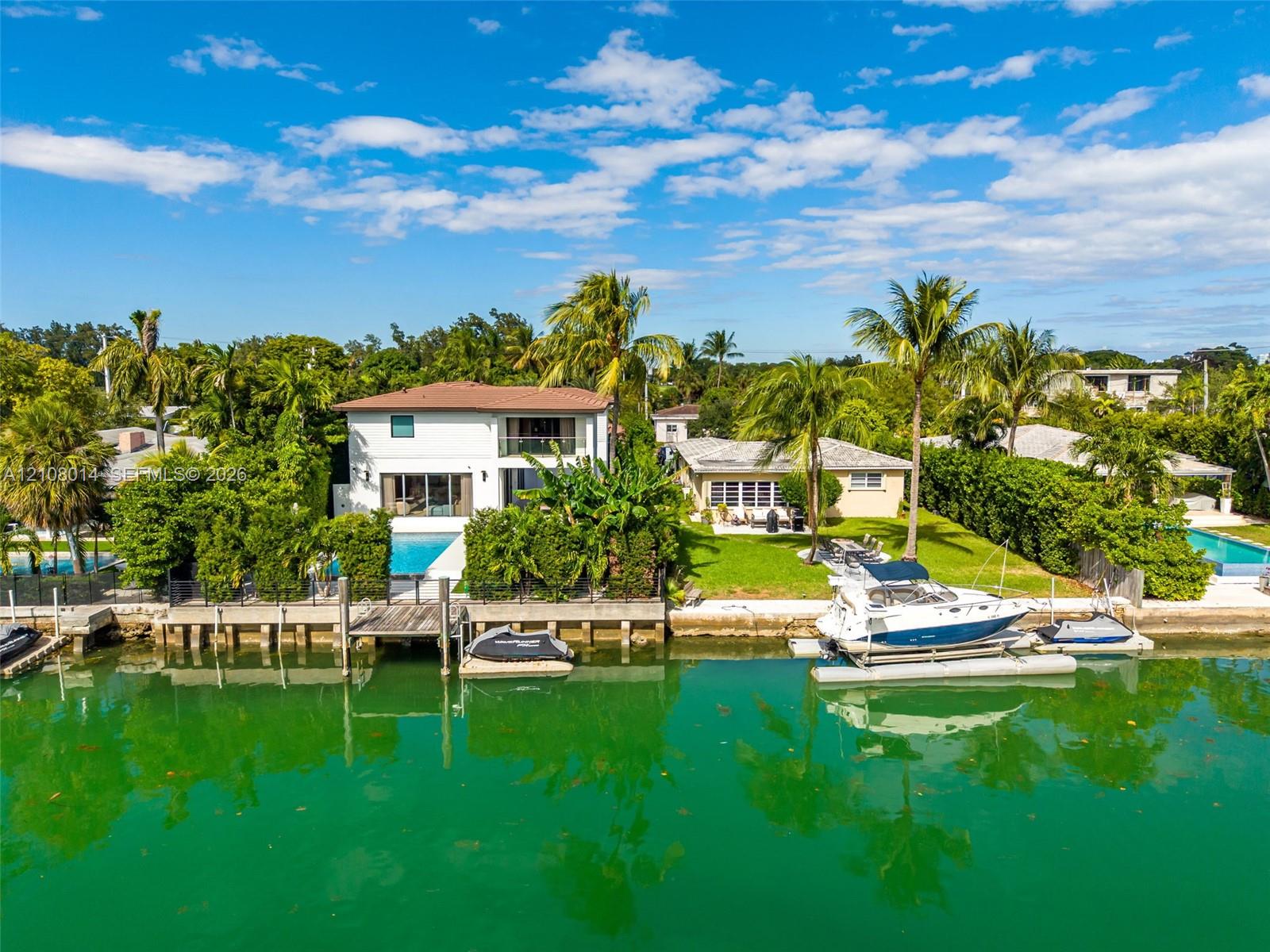 Waterfront residence featuring a private boat lift, deep-water dock, swimming pool, and multiple levels of outdoor living space