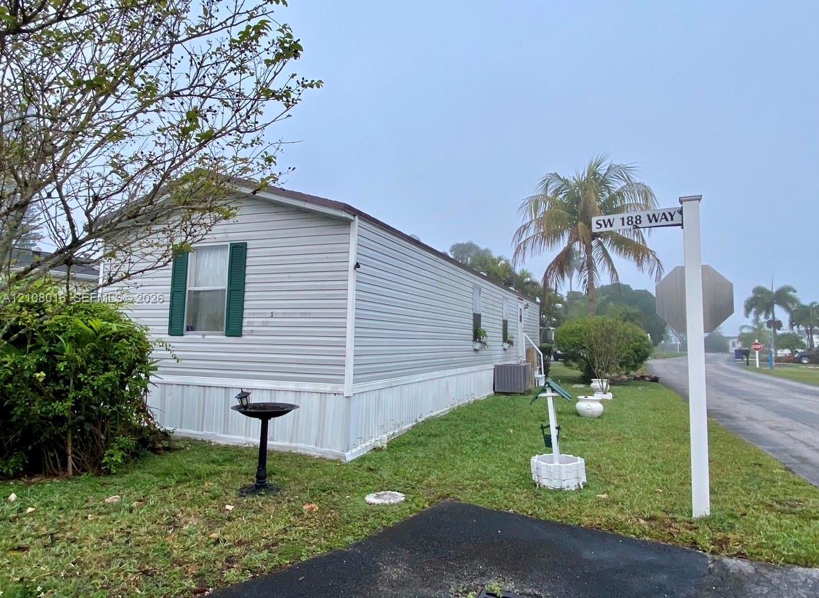 Light-colored horizontal siding, exterior shutters, and grass lawn