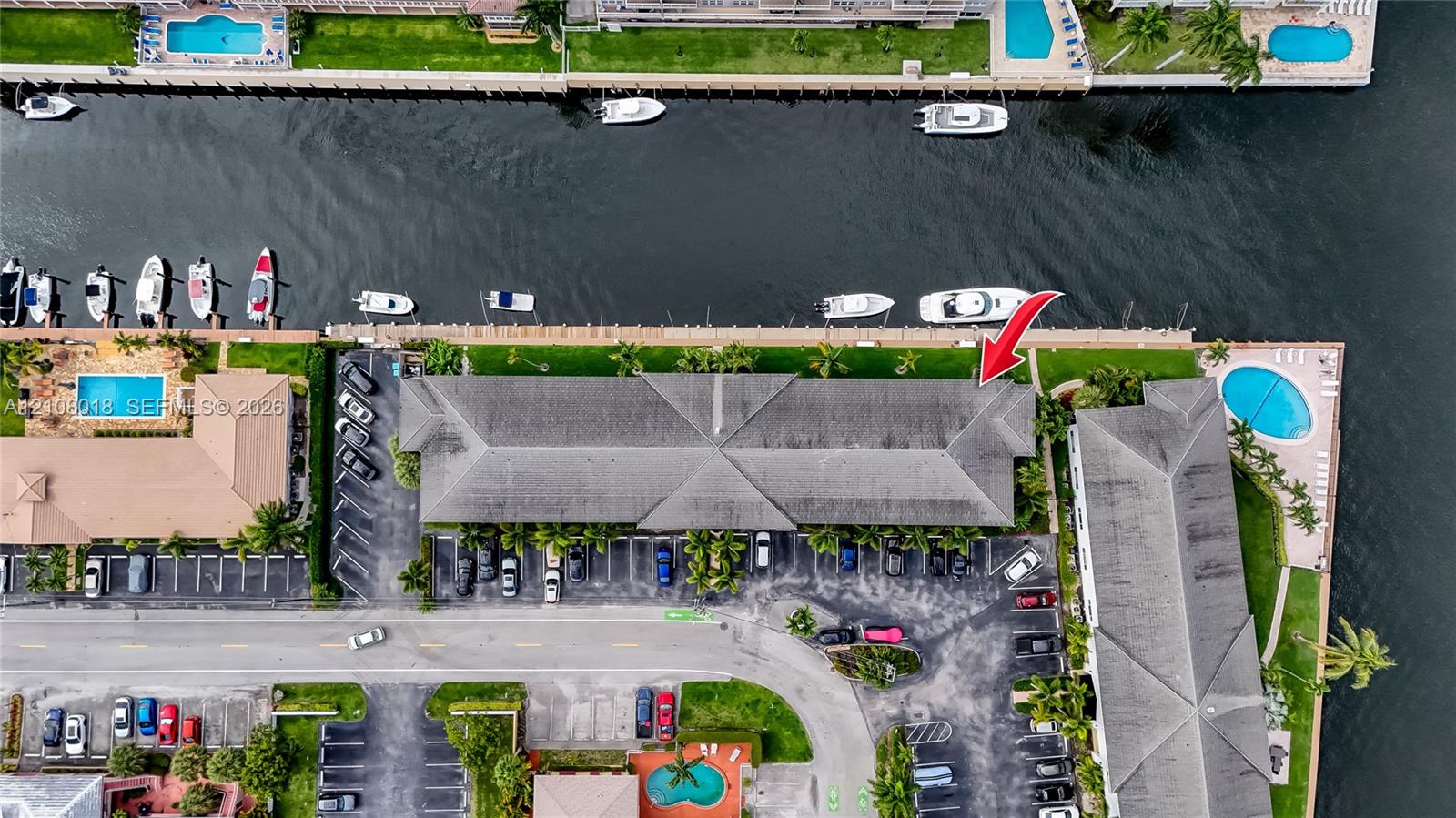 Aerial perspective of waterfront property featuring a concrete seawall, direct waterway access, private boat dockage, and paved surface parking