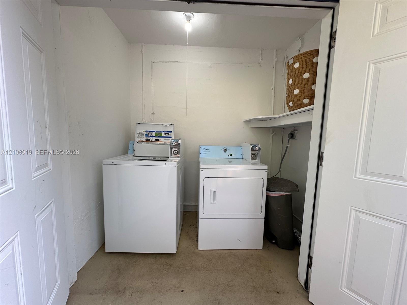 Laundry closet featuring dual white-finish laundry appliances and an integrated overhead storage shelf