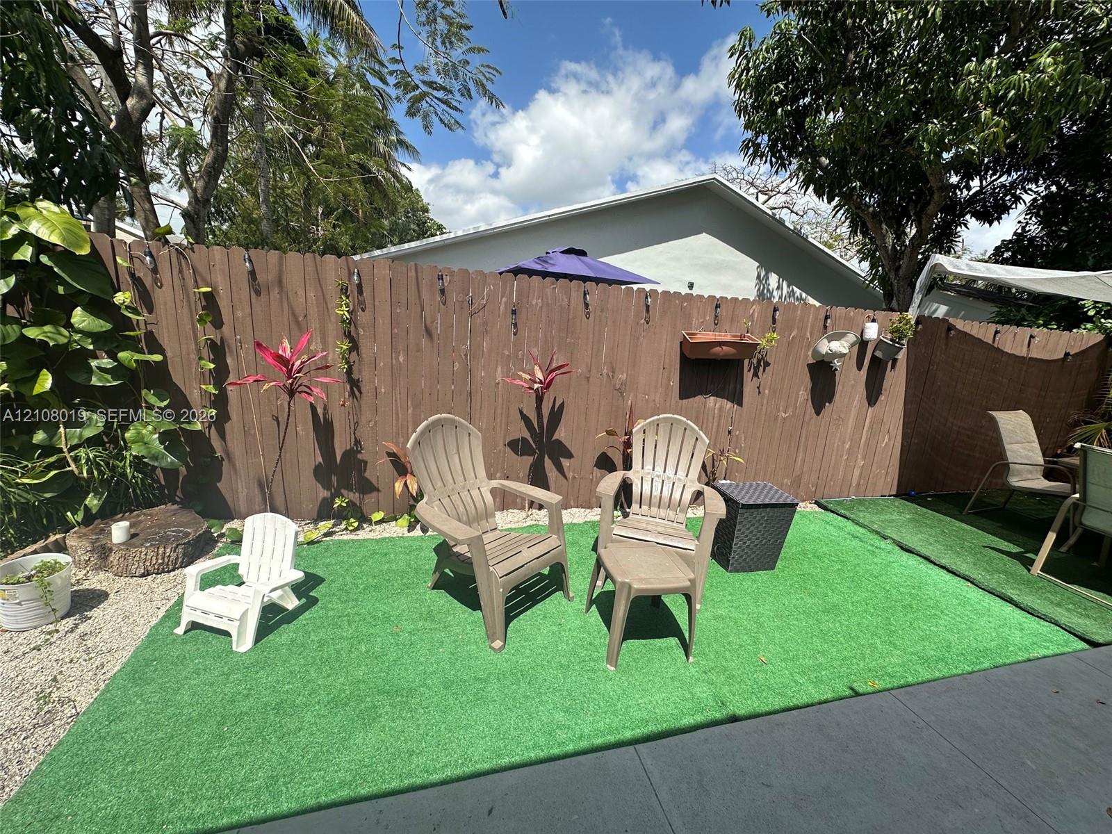 Fenced backyard featuring privacy screening, artificial turf, gravel hardscaping, and mature trees