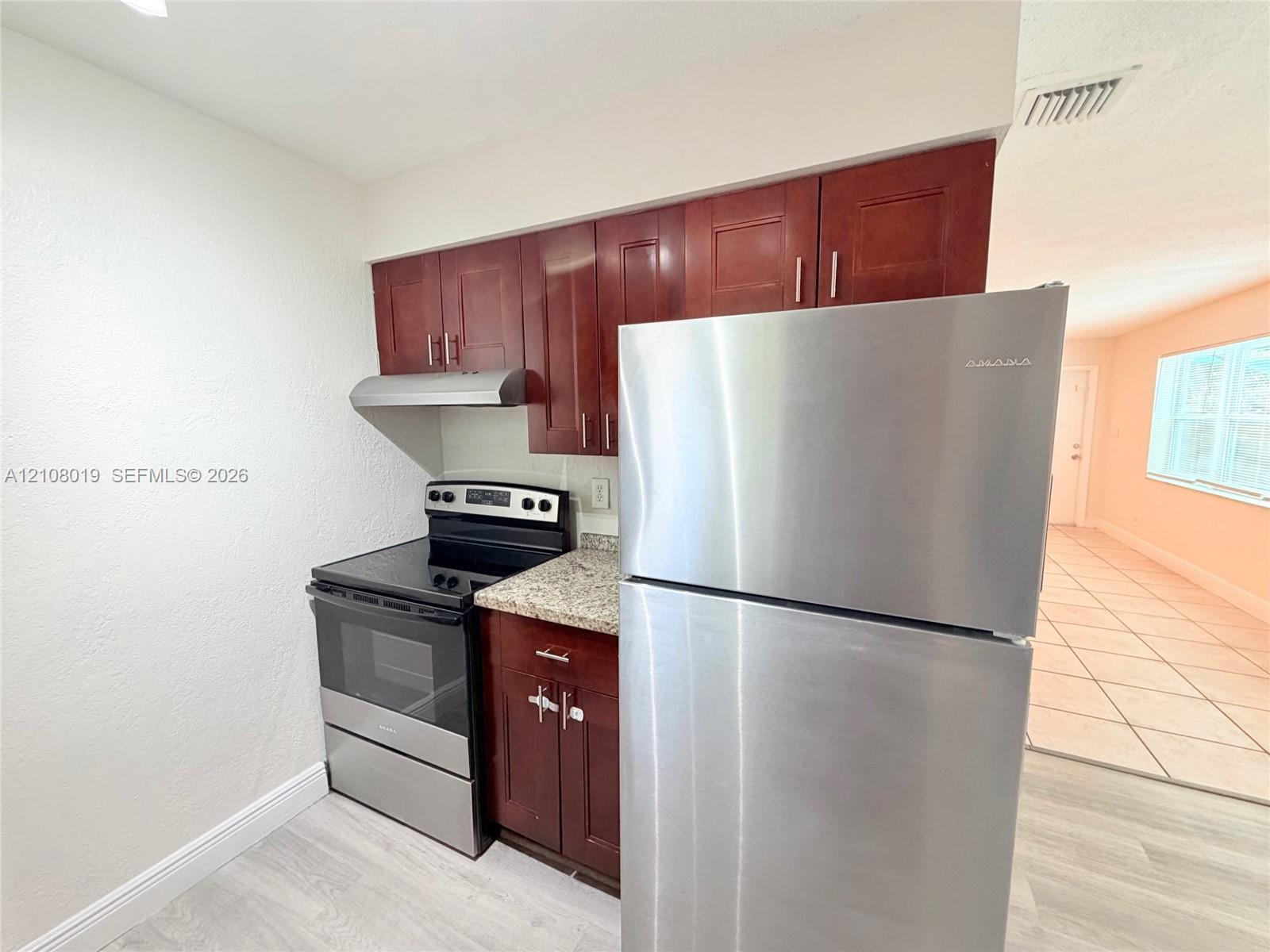 Kitchen featuring stained wood cabinetry, stone-finish countertops, and stainless steel appliances