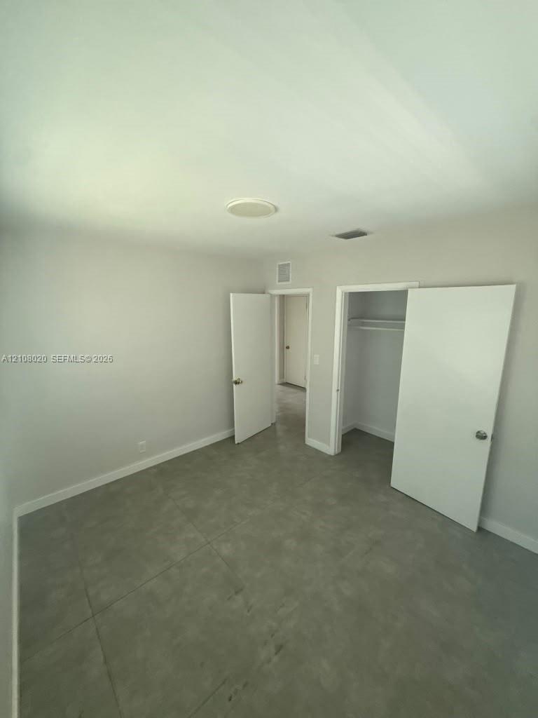 Neutral-toned interior room featuring large-format ceramic tile flooring, a recessed ceiling light, and a built-in closet with integrated shelving