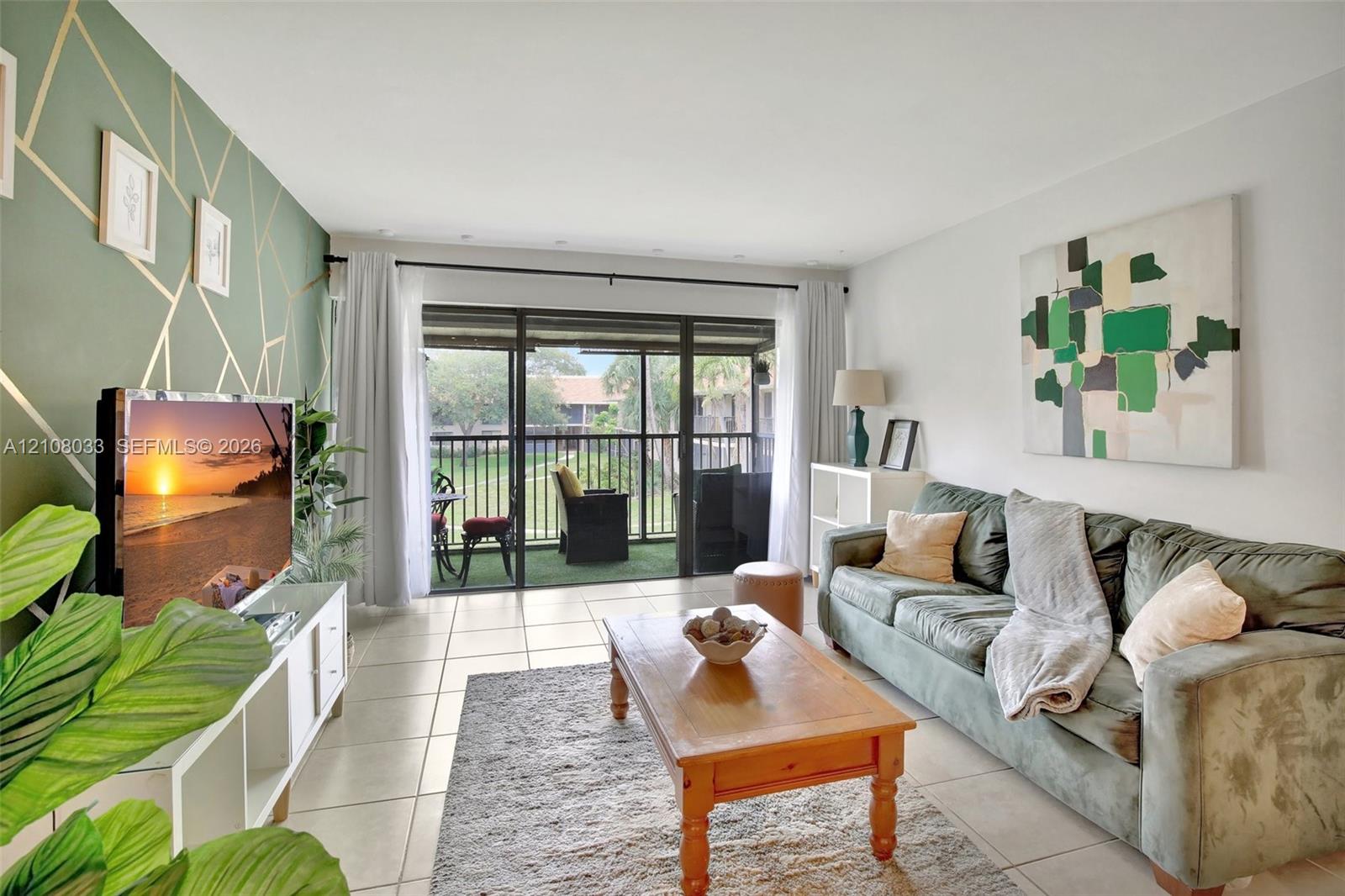 Living area featuring large-format tile flooring, a geometric-patterned accent wall, and sliding glass doors leading to a screened balcony
