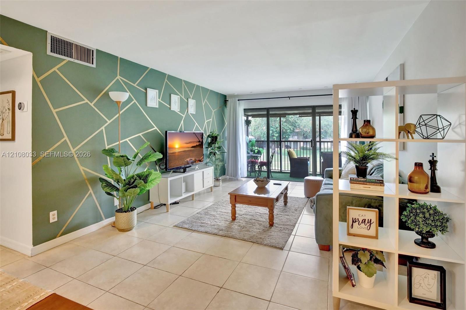Living area featuring large format tile flooring and floor-to-ceiling sliding glass doors opening to a screened-in patio