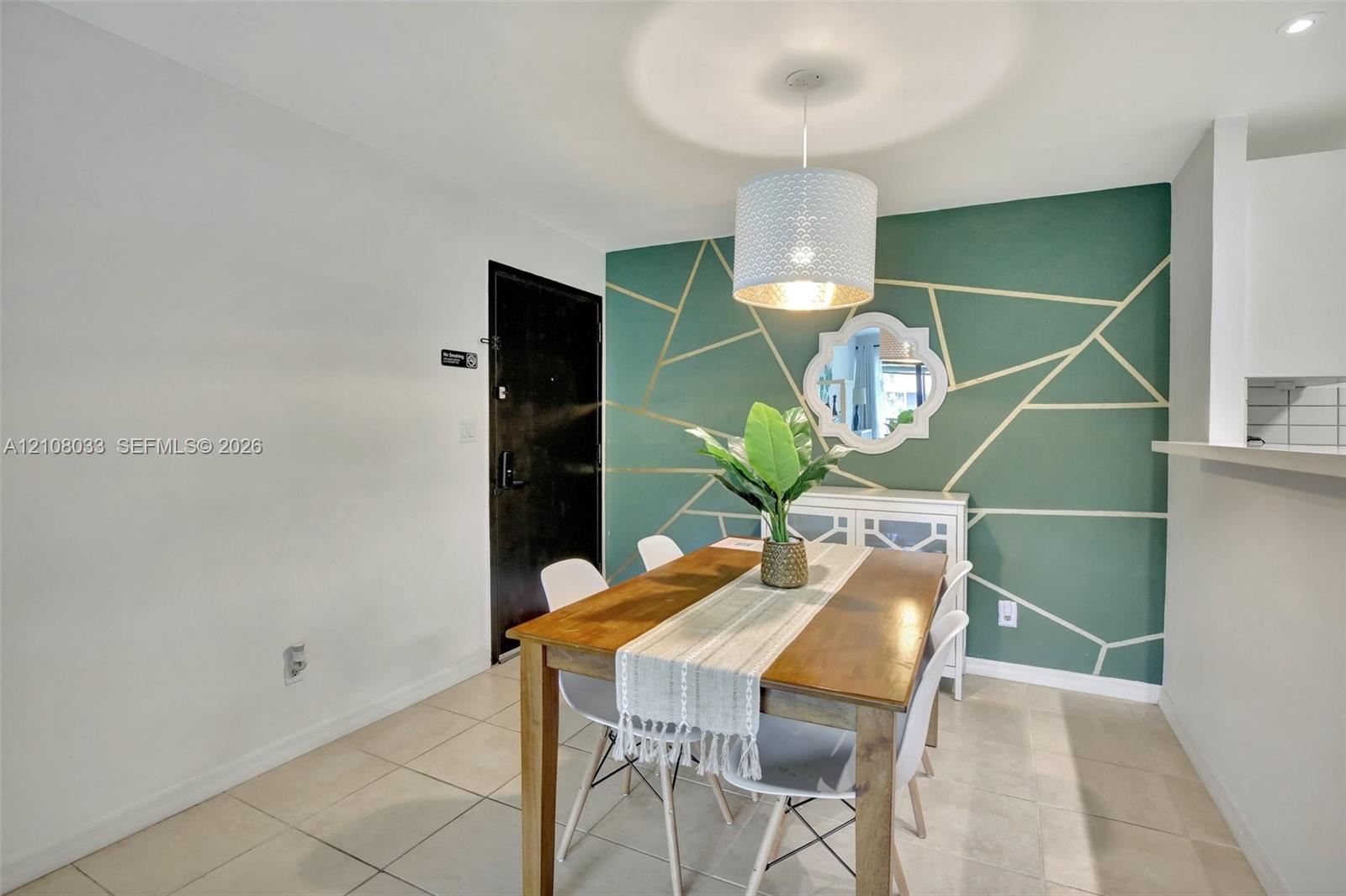 Geometric accent wall with gold-toned detailing, neutral tile flooring, and suspended drum pendant lighting