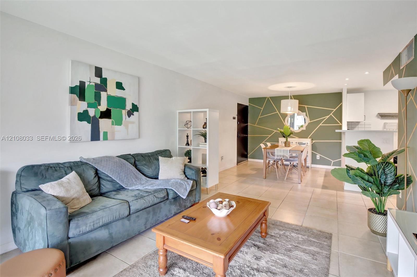 Open-concept interior featuring neutral tile flooring, an accent wall with geometric wall molding, and recessed lighting