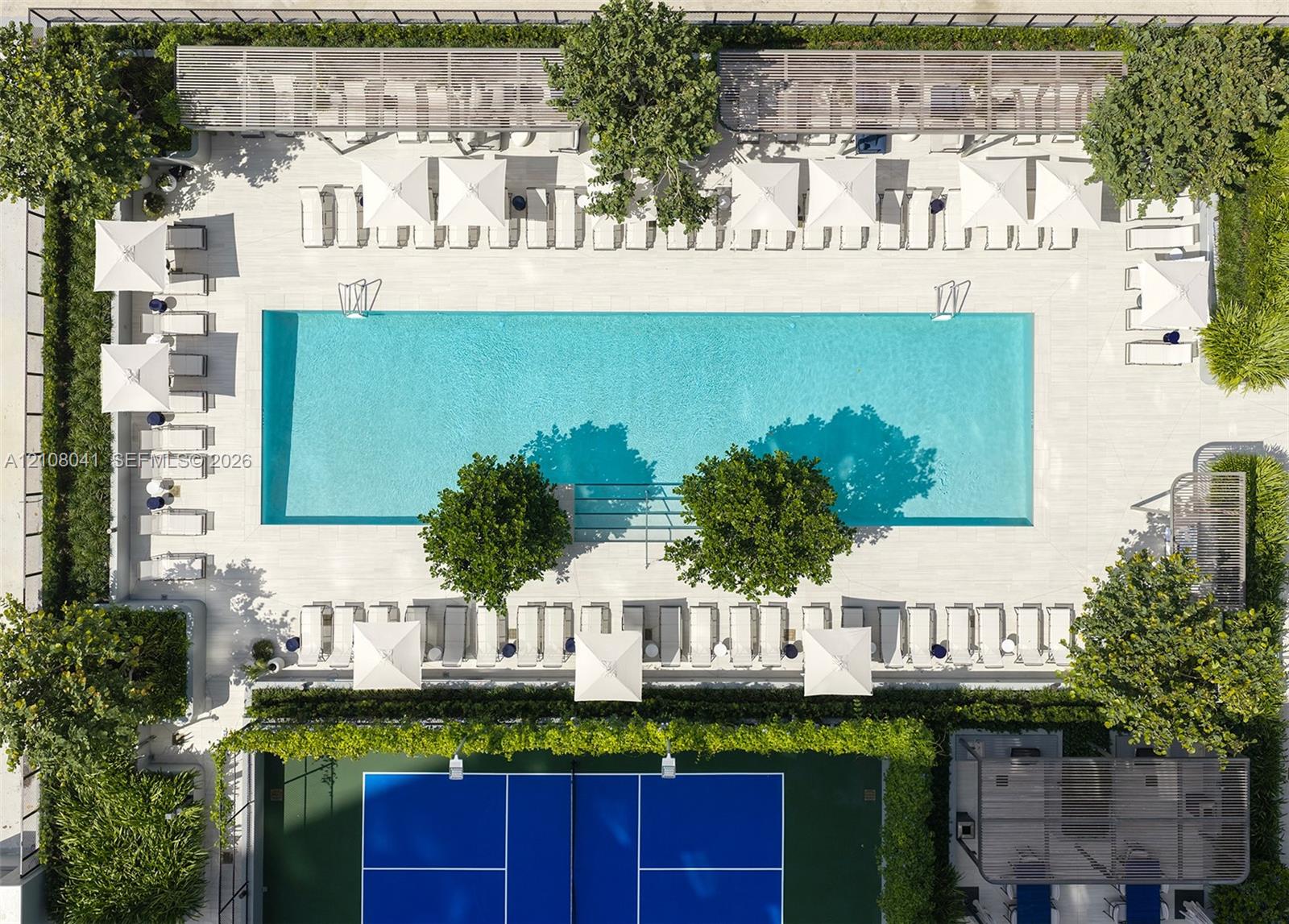 Rectangular swimming pool with stone-surround decking, enclosed tennis court, integrated metal pergolas, and established perimeter landscaping