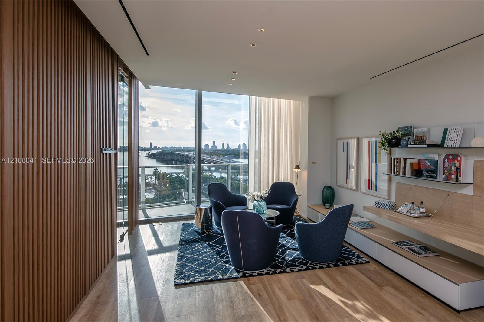 Floor-to-ceiling glass windows, wood-finish flooring, custom wood-slat wall paneling, built-in wall shelving, and an integrated balcony
