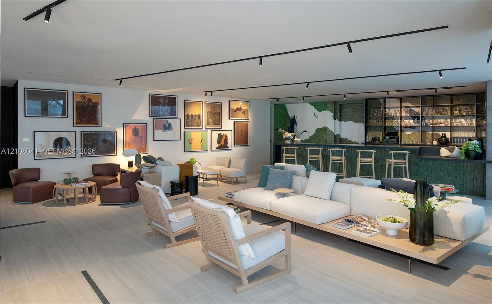Light wood-finish flooring with track lighting, an integrated bar area with a textured green counter, and a back wall featuring a glass-front display