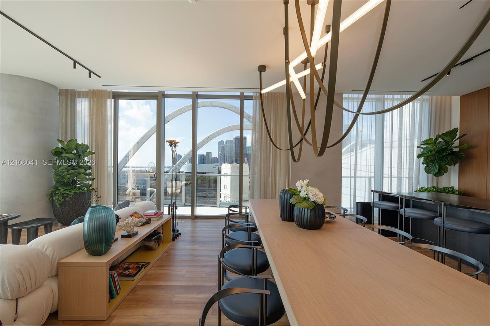 Open-concept living area featuring wood-finish flooring, floor-to-ceiling glass doors, and a linear track lighting system